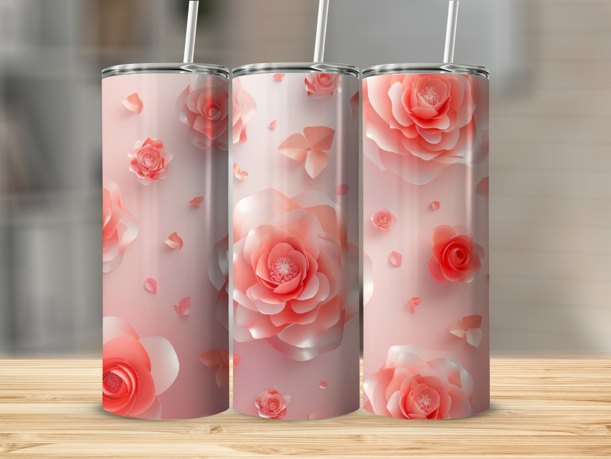 Three tall pink floral tumblers with straws on a wooden surface.