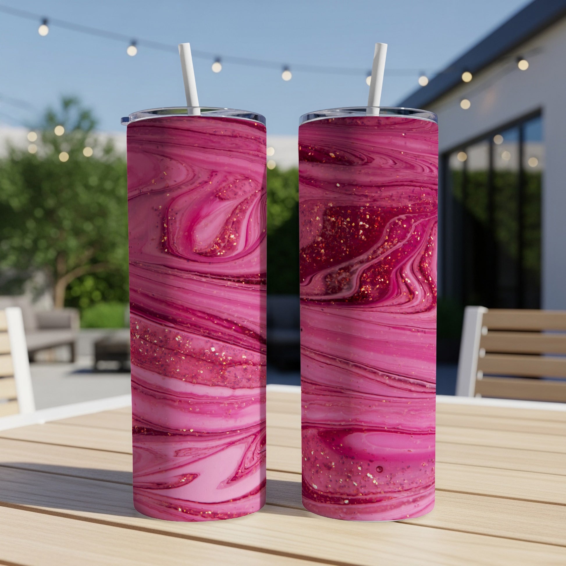 Two pink marbled tumblers with gold glitter accents on a wooden table.