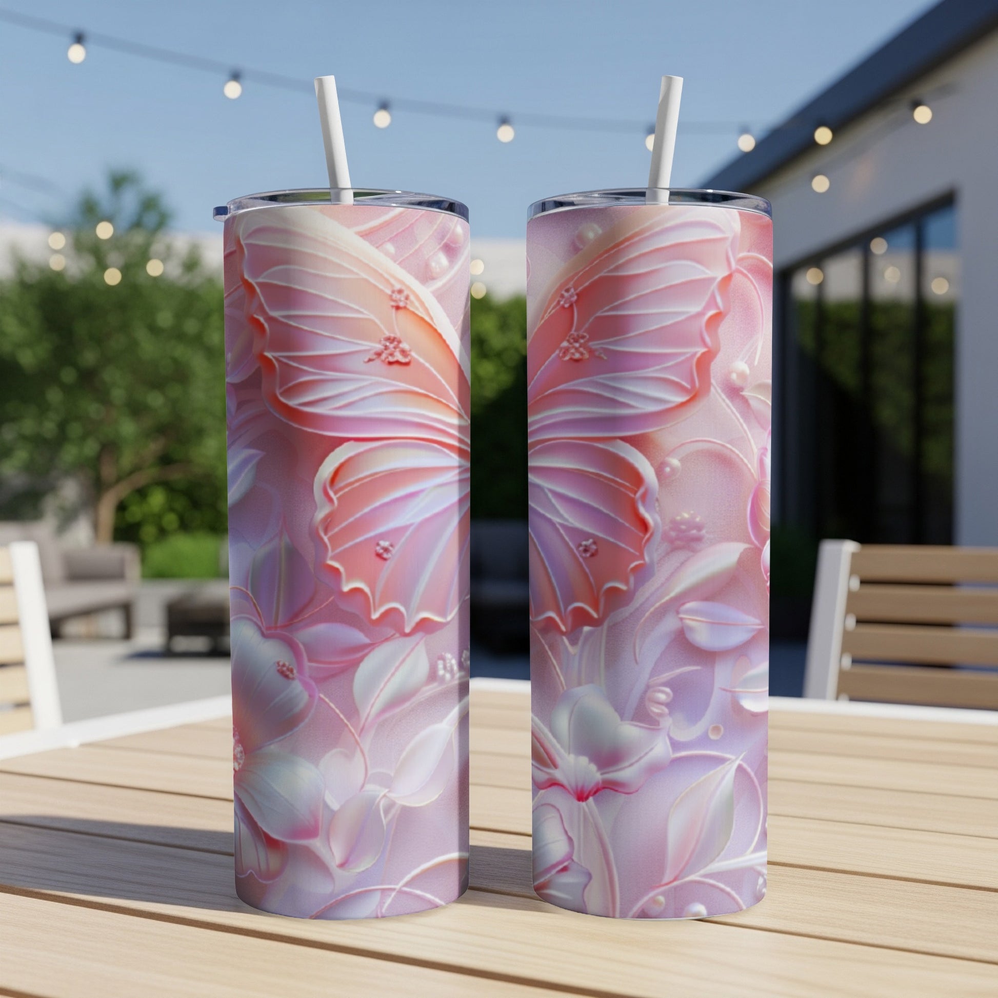Two pink butterfly design tumblers with straws on a wooden table.