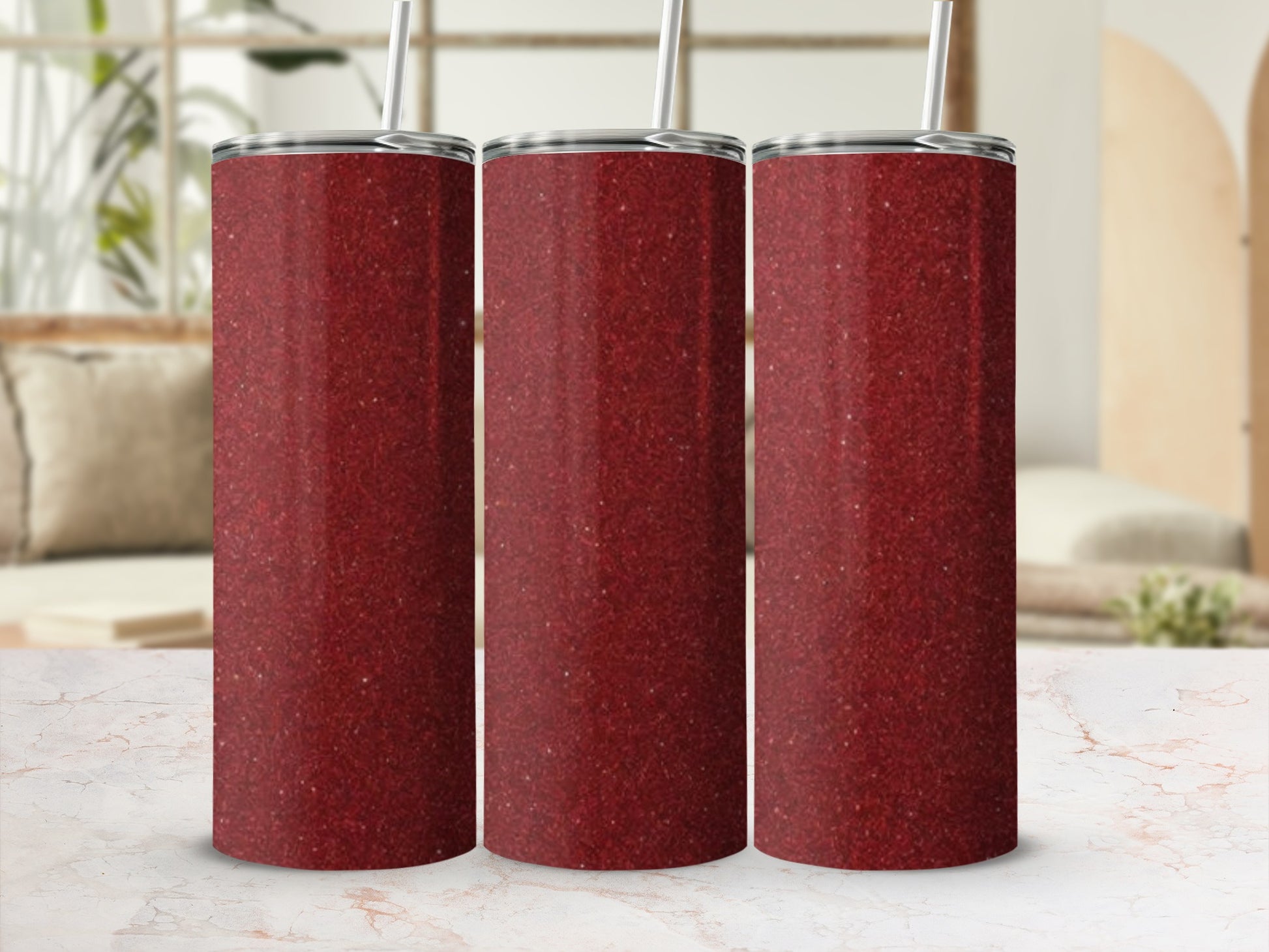 Three red glitter tumblers with straws on a marble surface.