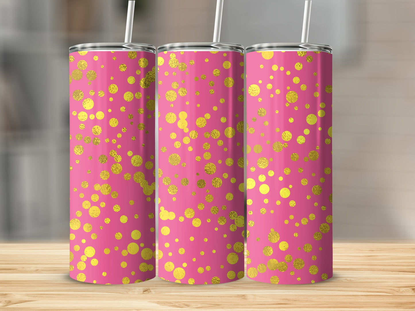 Three pink tumblers with gold polka dot pattern on a wooden surface.
