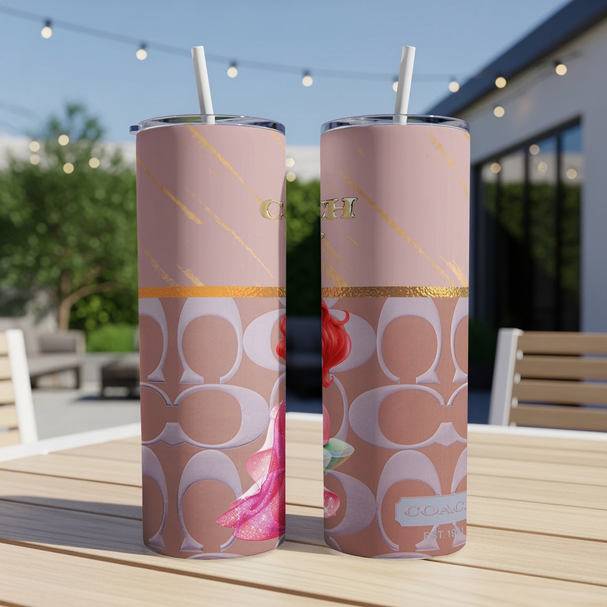 Two pink tumblers with Coach logo and Disney's Ariel design, straws inserted.