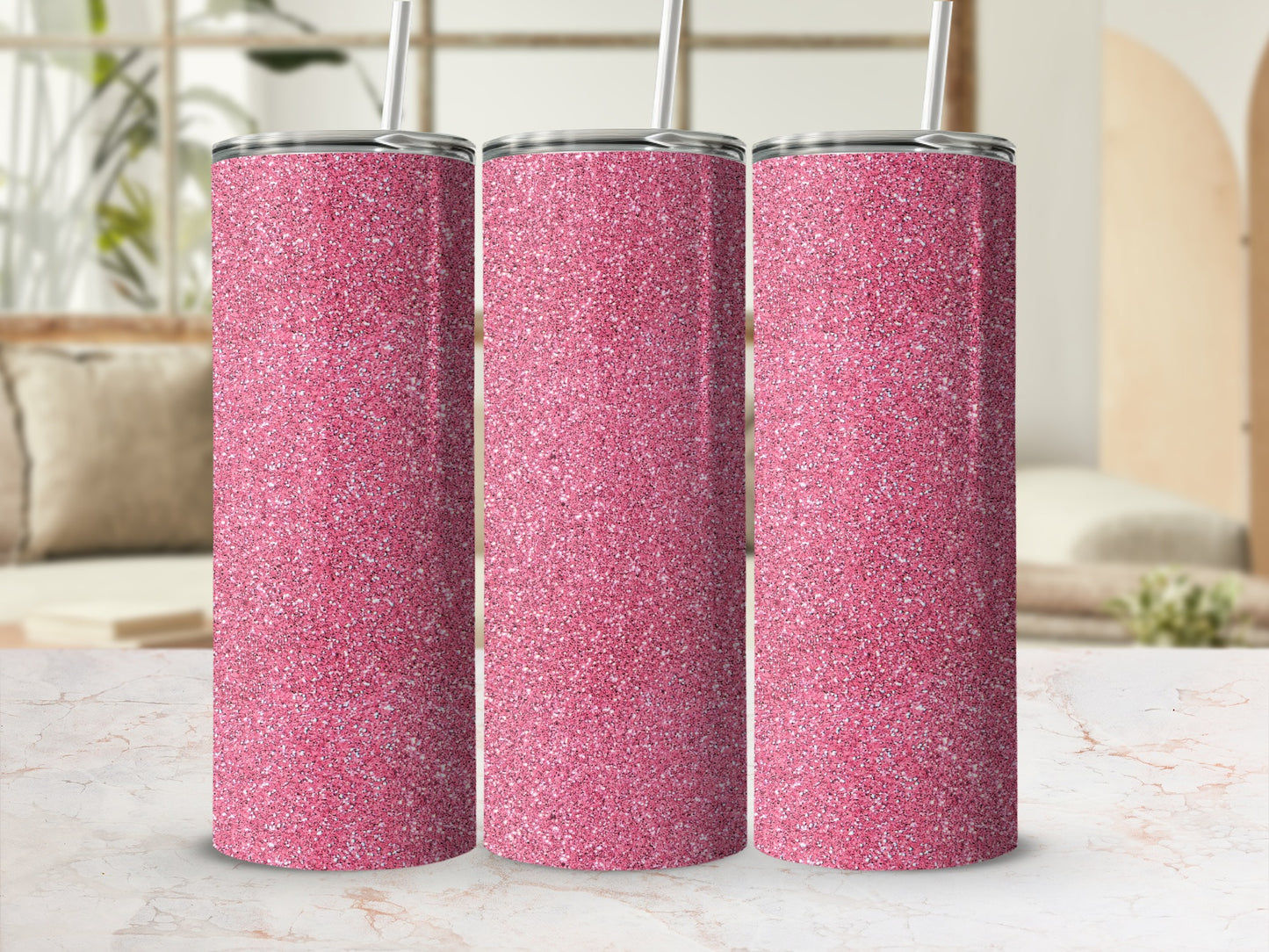 Three pink glitter tumblers with silver lids and straws on a marble surface.