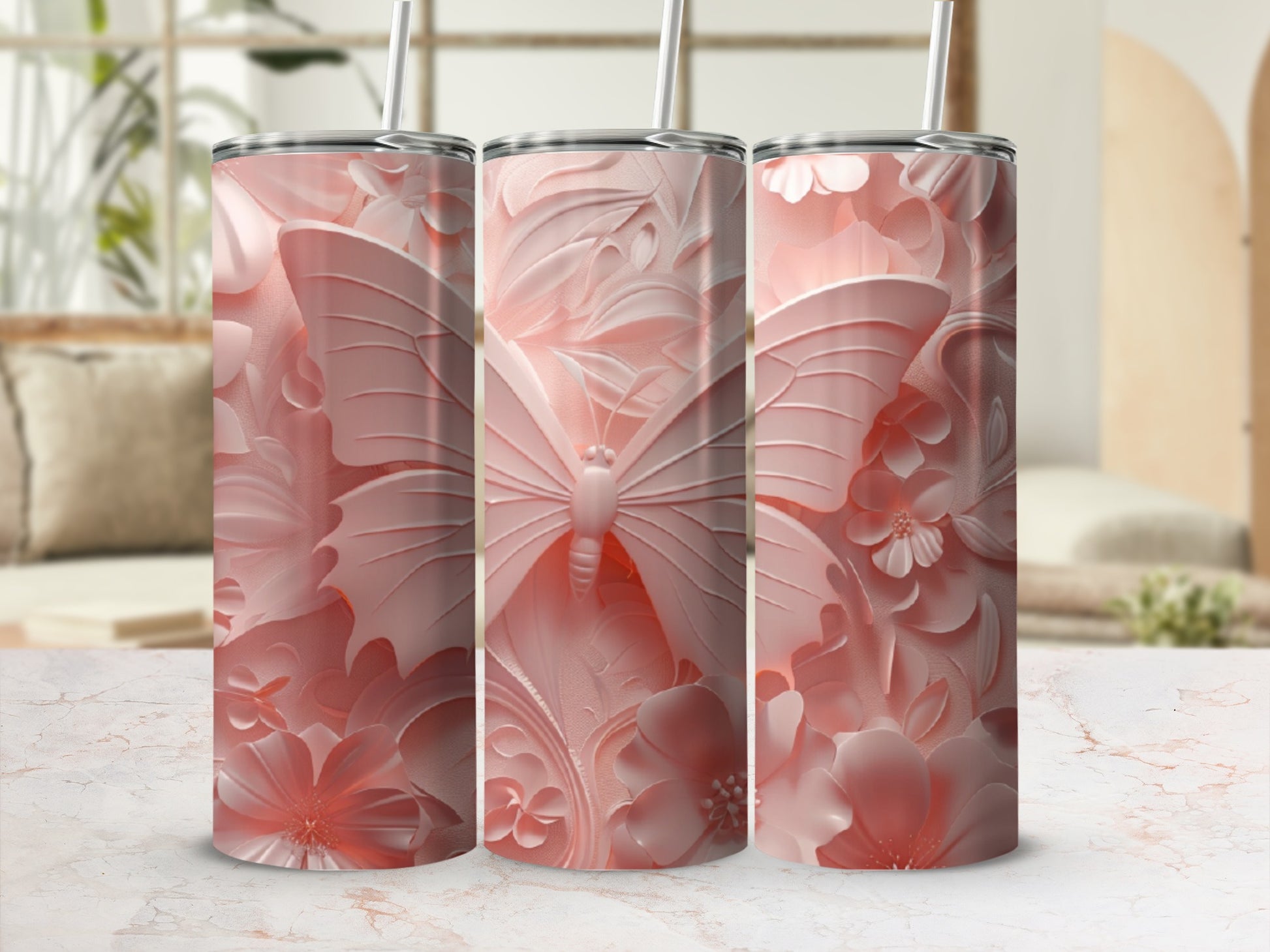 Three pink floral and butterfly patterned tumblers with straws.