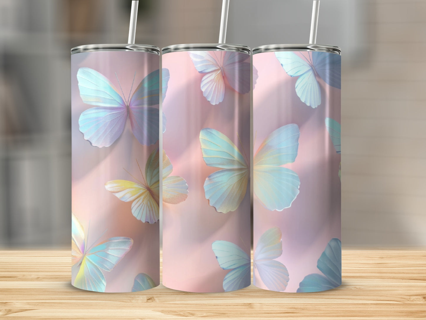Three tumblers with pastel butterfly design on a wooden surface.