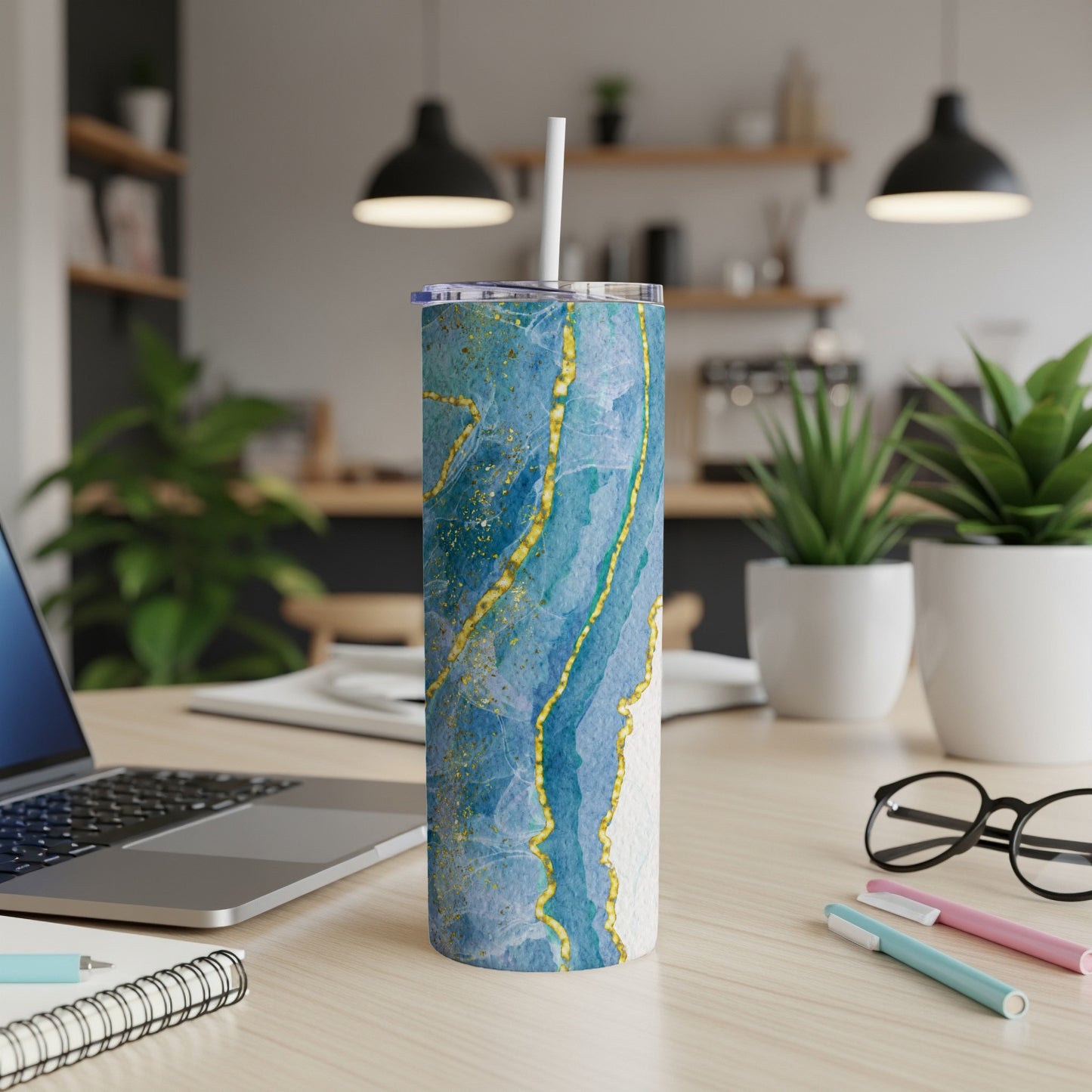 Blue and gold marbled tumbler with white lid and straw on a desk.