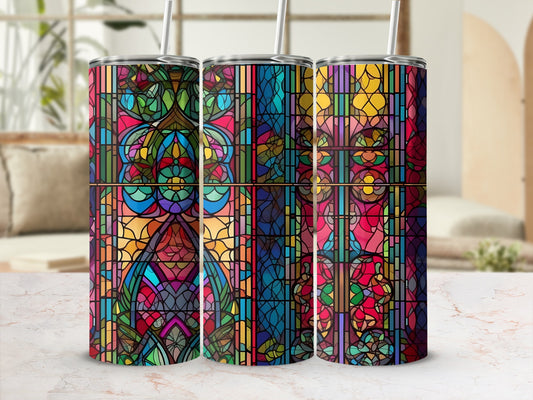 Three colorful stained glass tumblers with straws sit on a marble countertop.