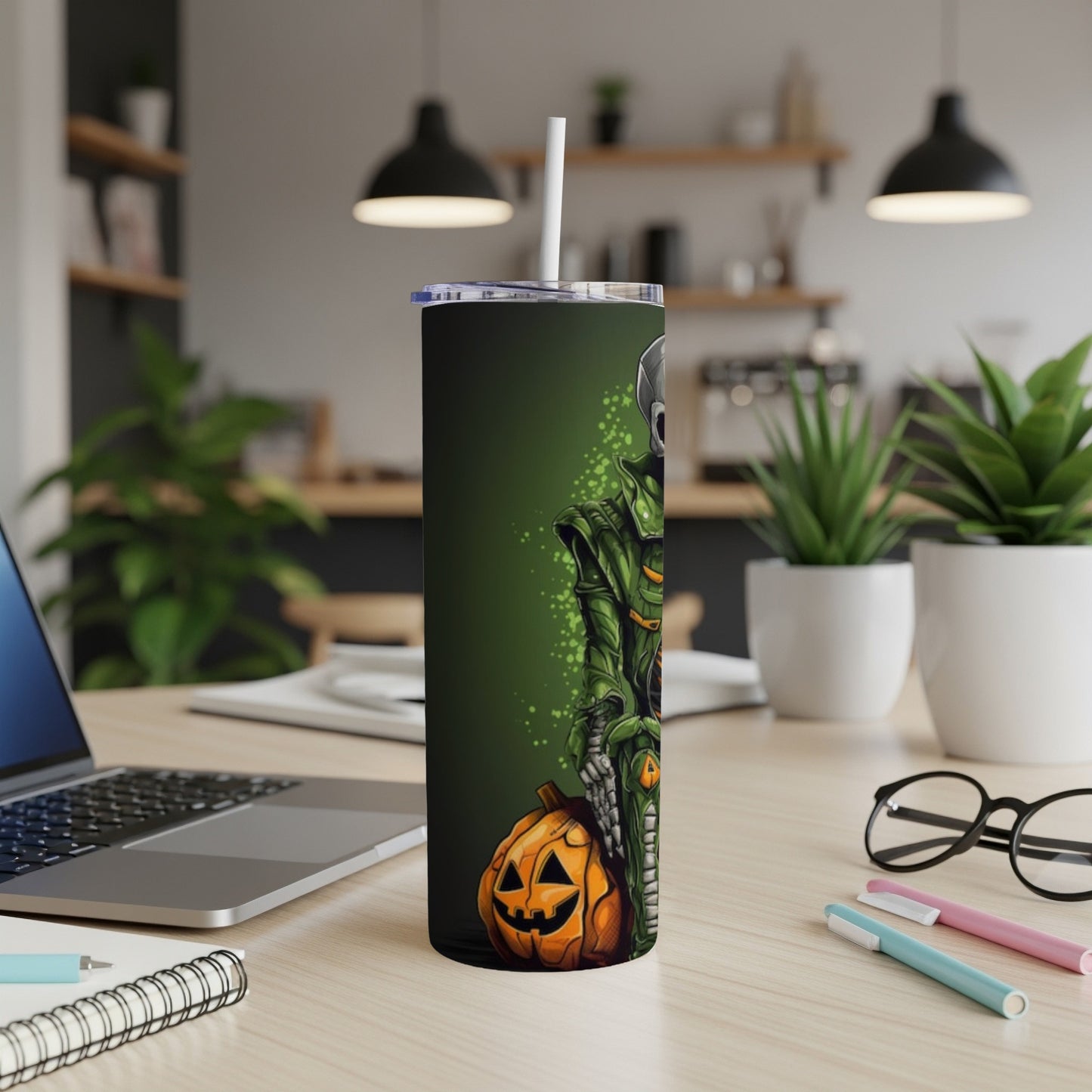 Halloween tumbler with skeleton, pumpkin, and green accents on a desk.