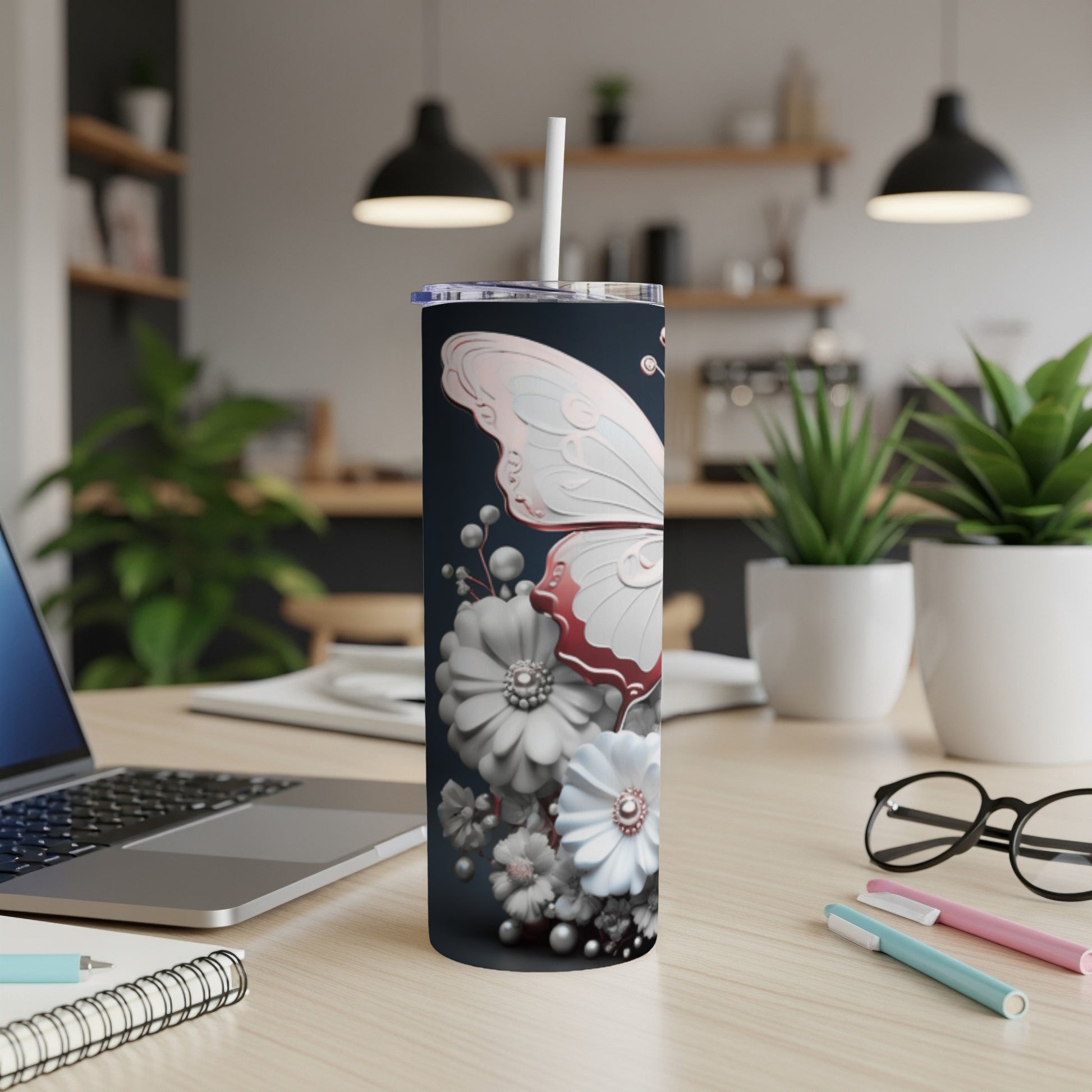 Dark tumbler with white butterfly and floral design, straw inserted.