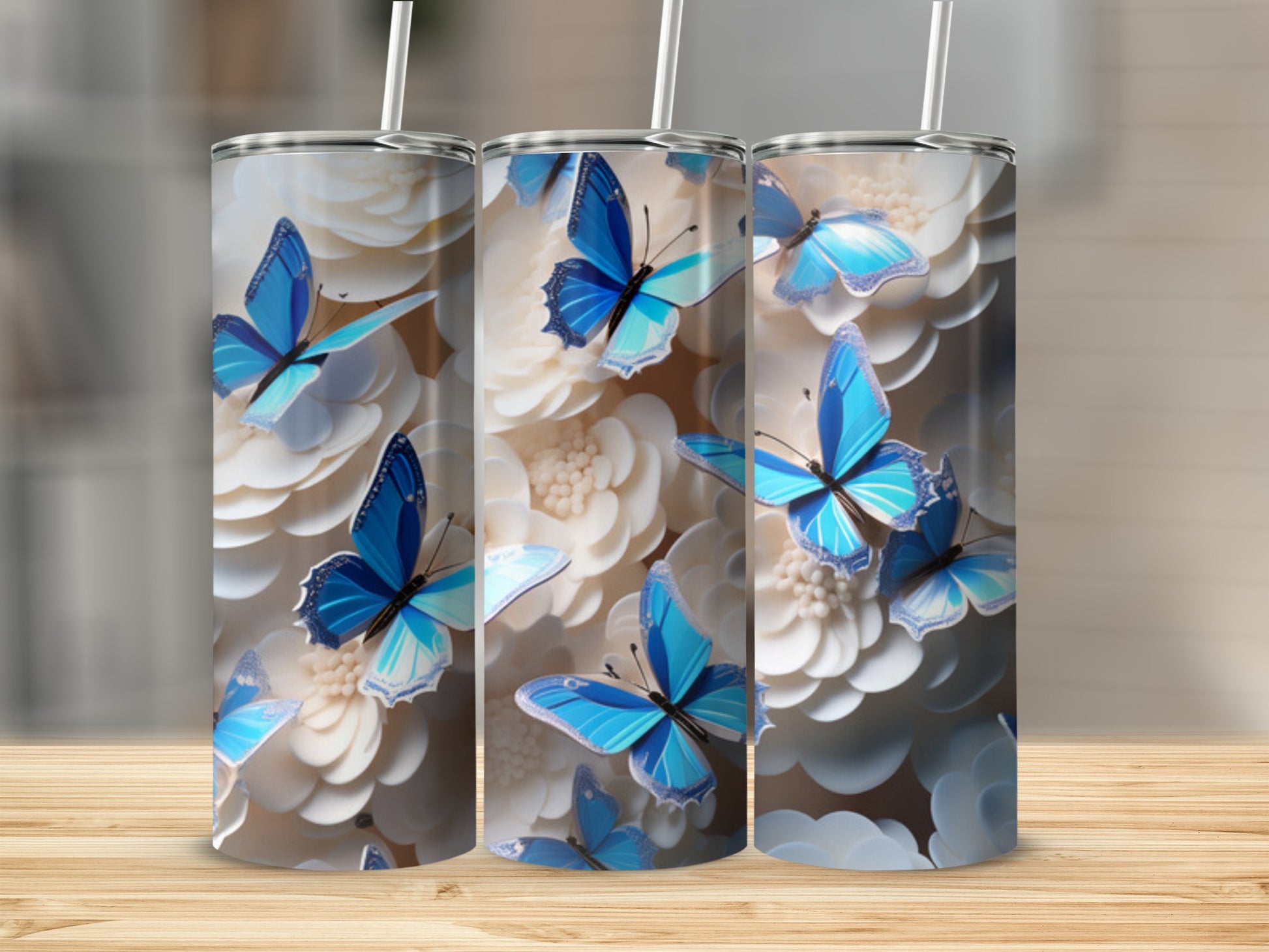 Three tumblers with blue butterflies and white flowers on a wooden surface.