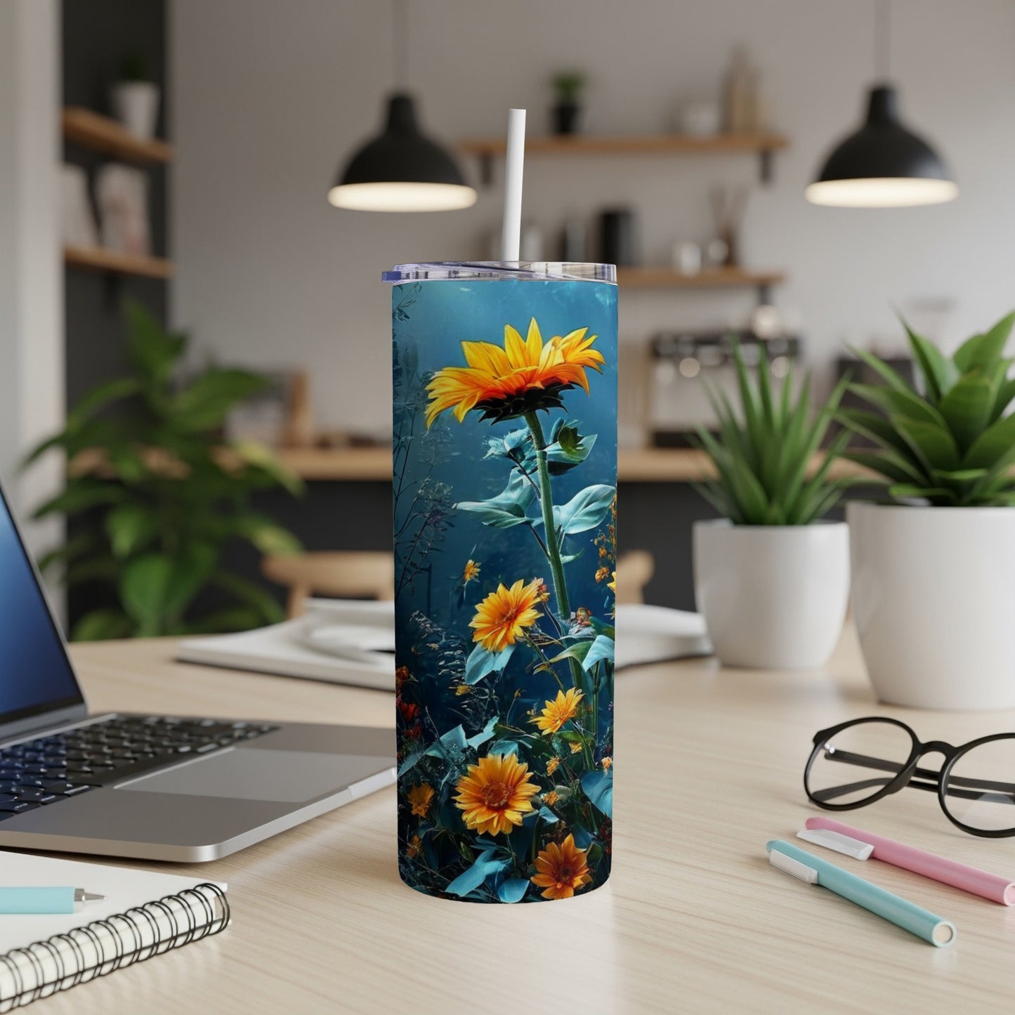 Sunflower and floral design on a tall, slender tumbler on a desk.