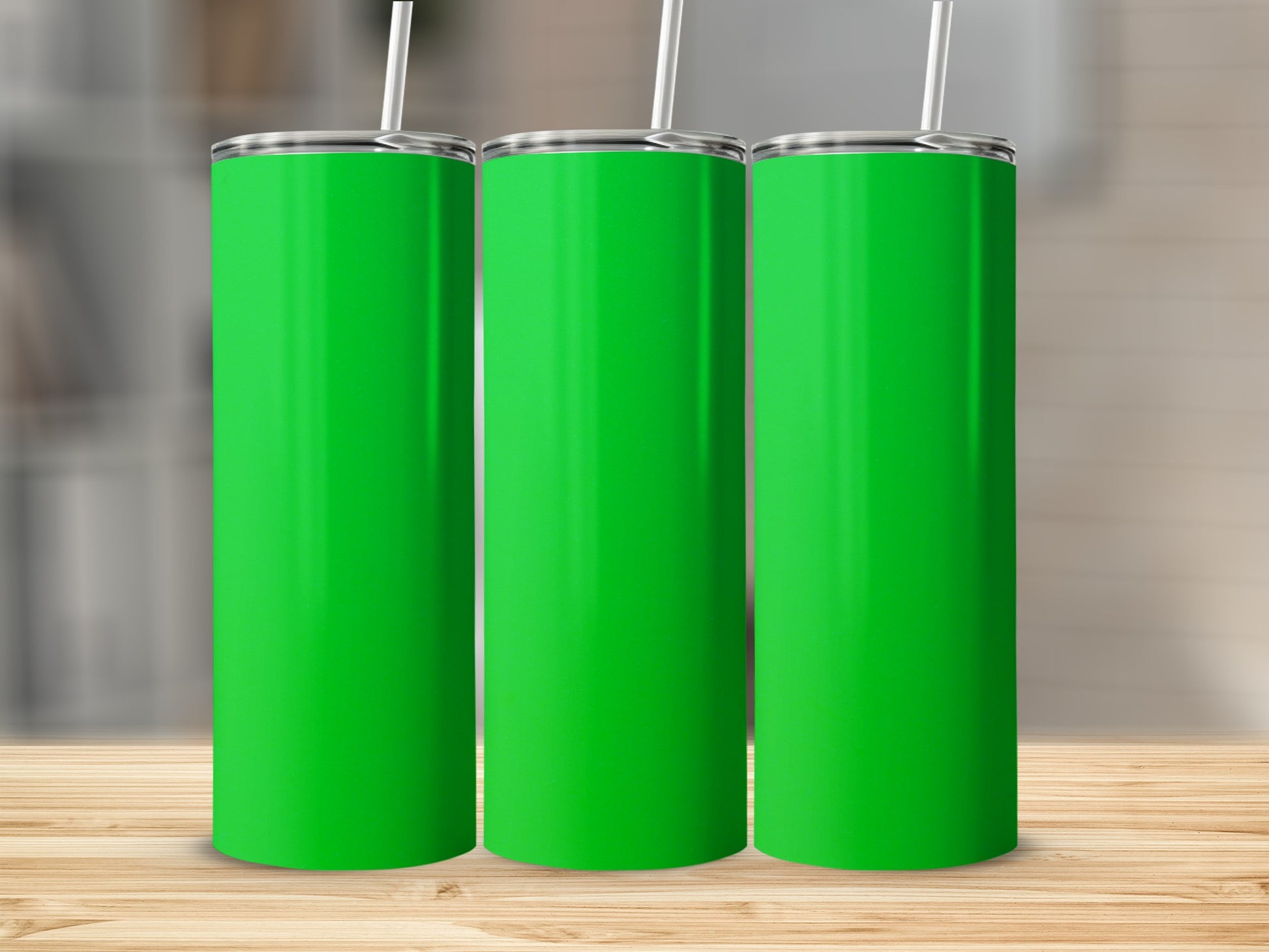 Three plain green tumblers with white straws stand on a wooden surface.