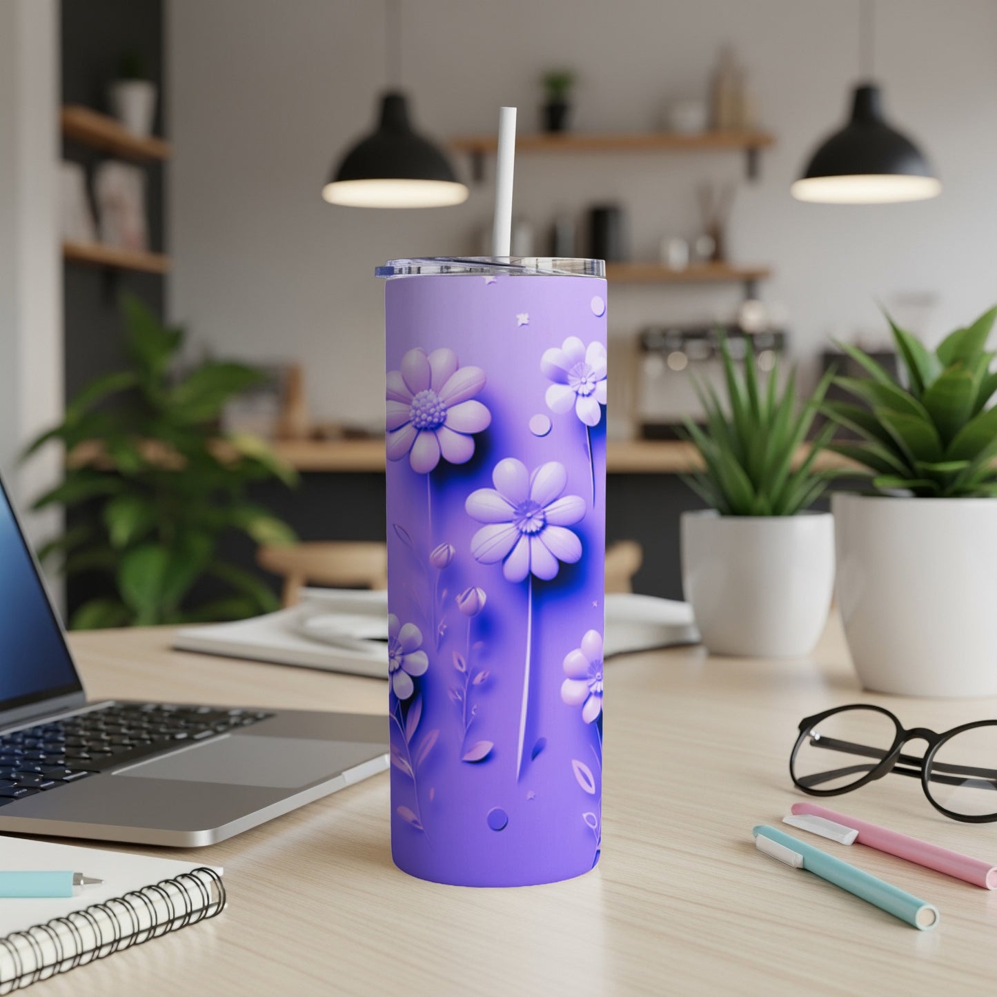 Purple tumbler with white floral pattern and straw on a desk.
