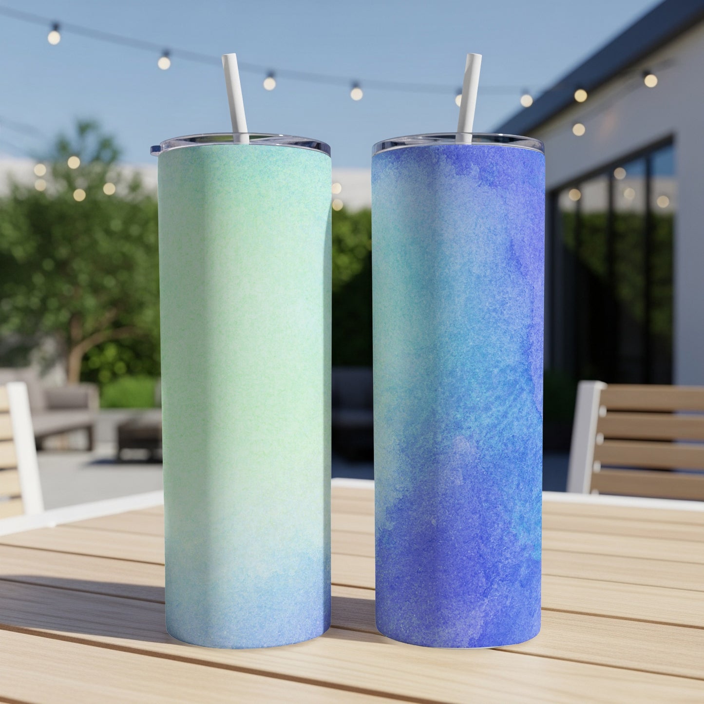 Two tumblers with blue and green watercolor designs on a wooden table.