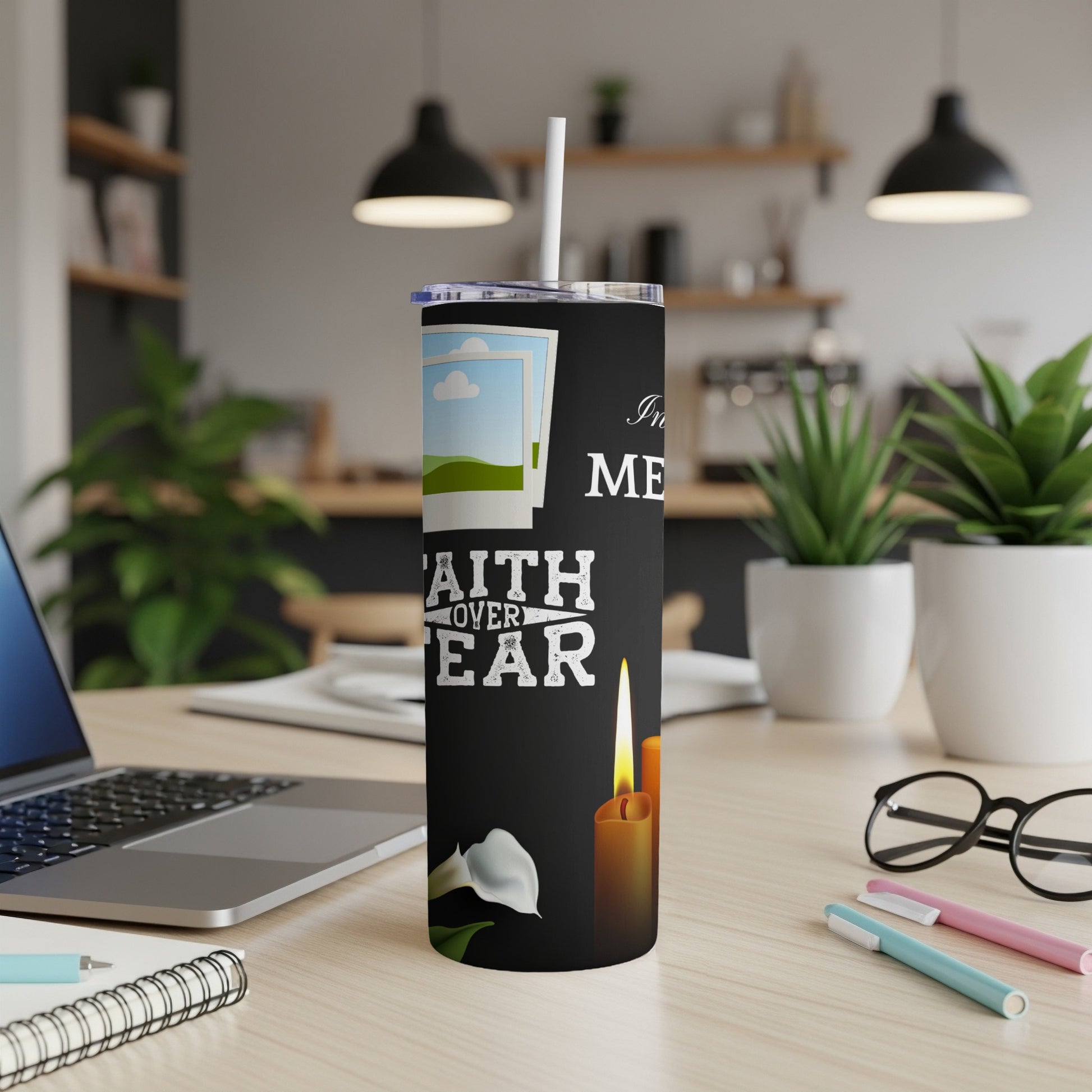 Black tumbler with "FAITH OVER FEAR" and candle graphics, on a desk.