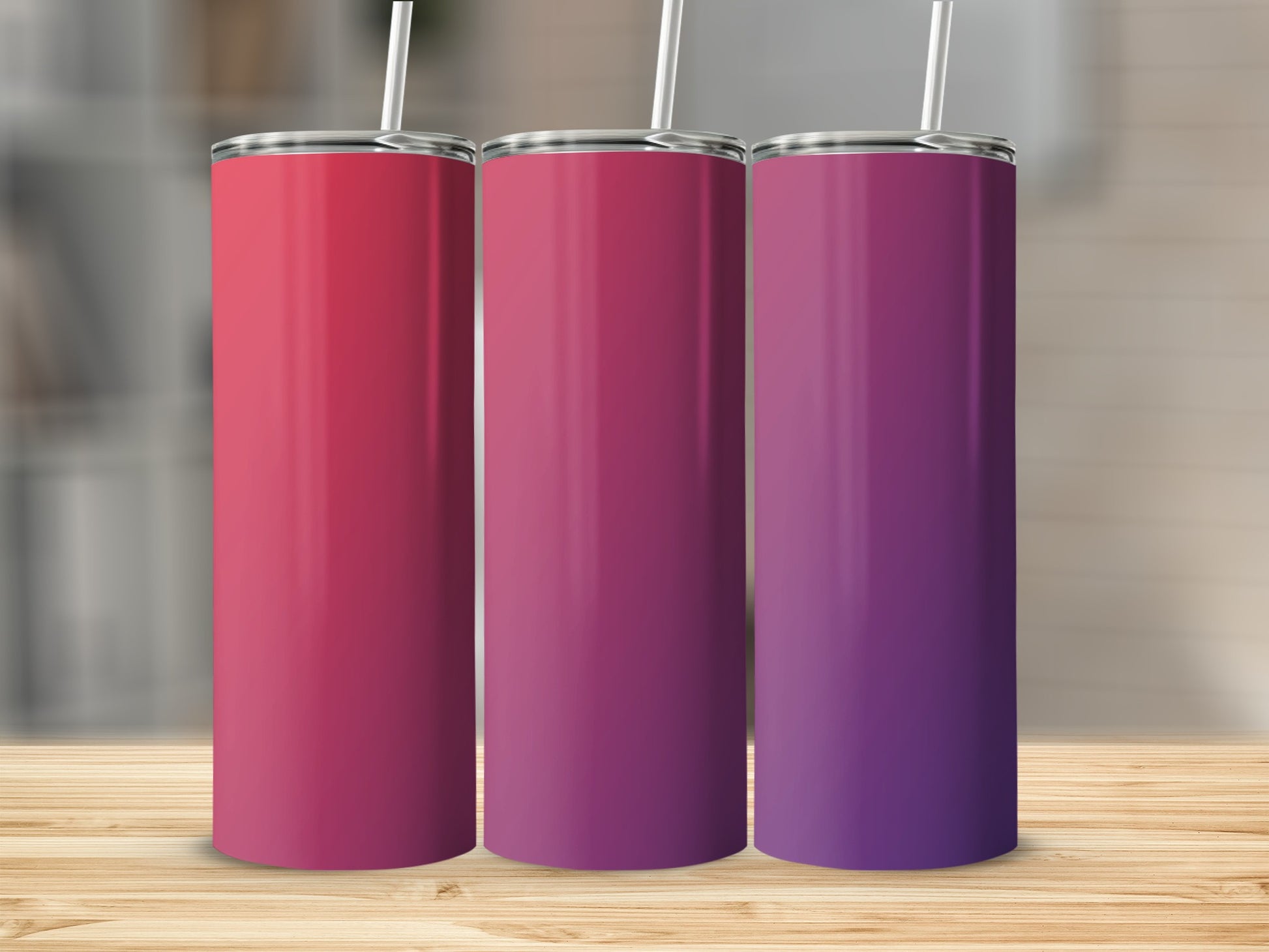 Three gradient tumblers with straws on a wooden surface.