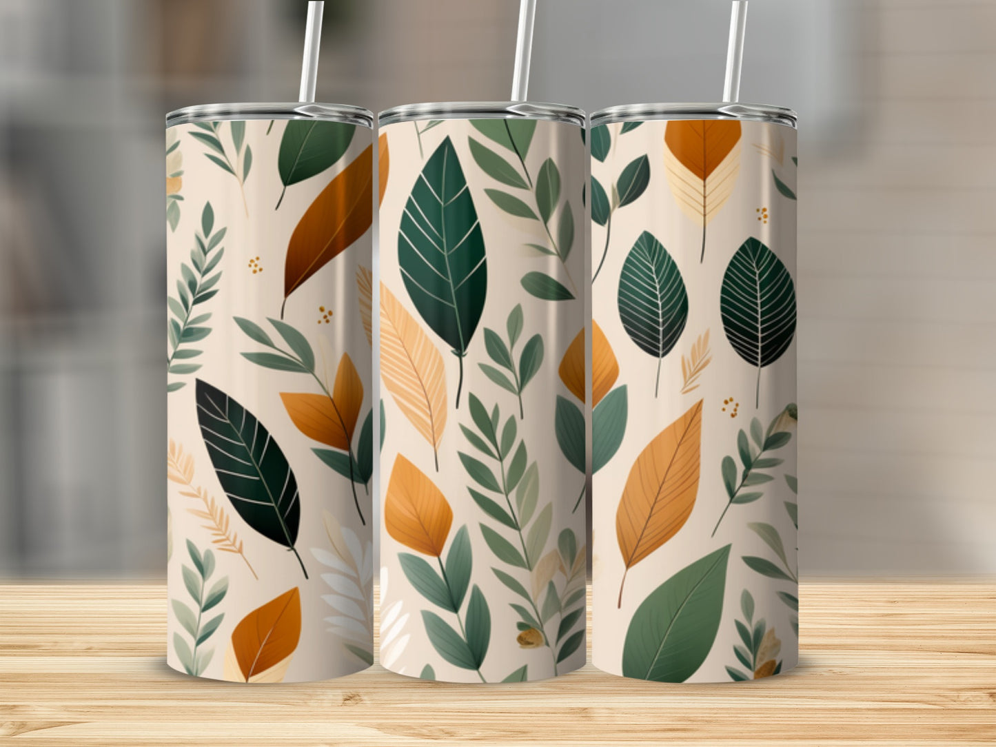 Three tumblers with a repeating pattern of various green and orange leaves on a light background.