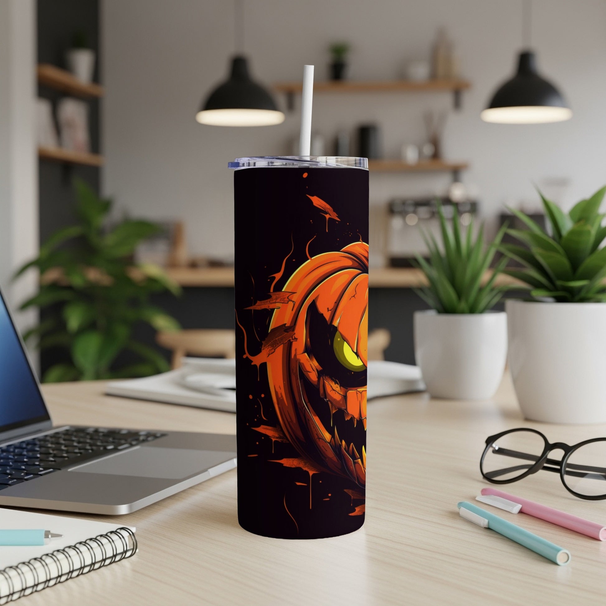 Tumbler with a scary jack-o'-lantern illustration, black background, straw, and lid.