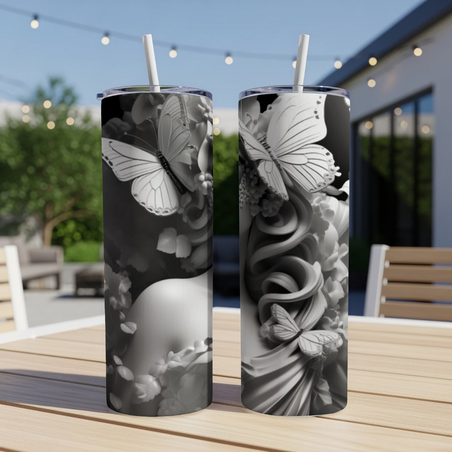 Two tumblers with a swirling floral and butterfly design on a table.
