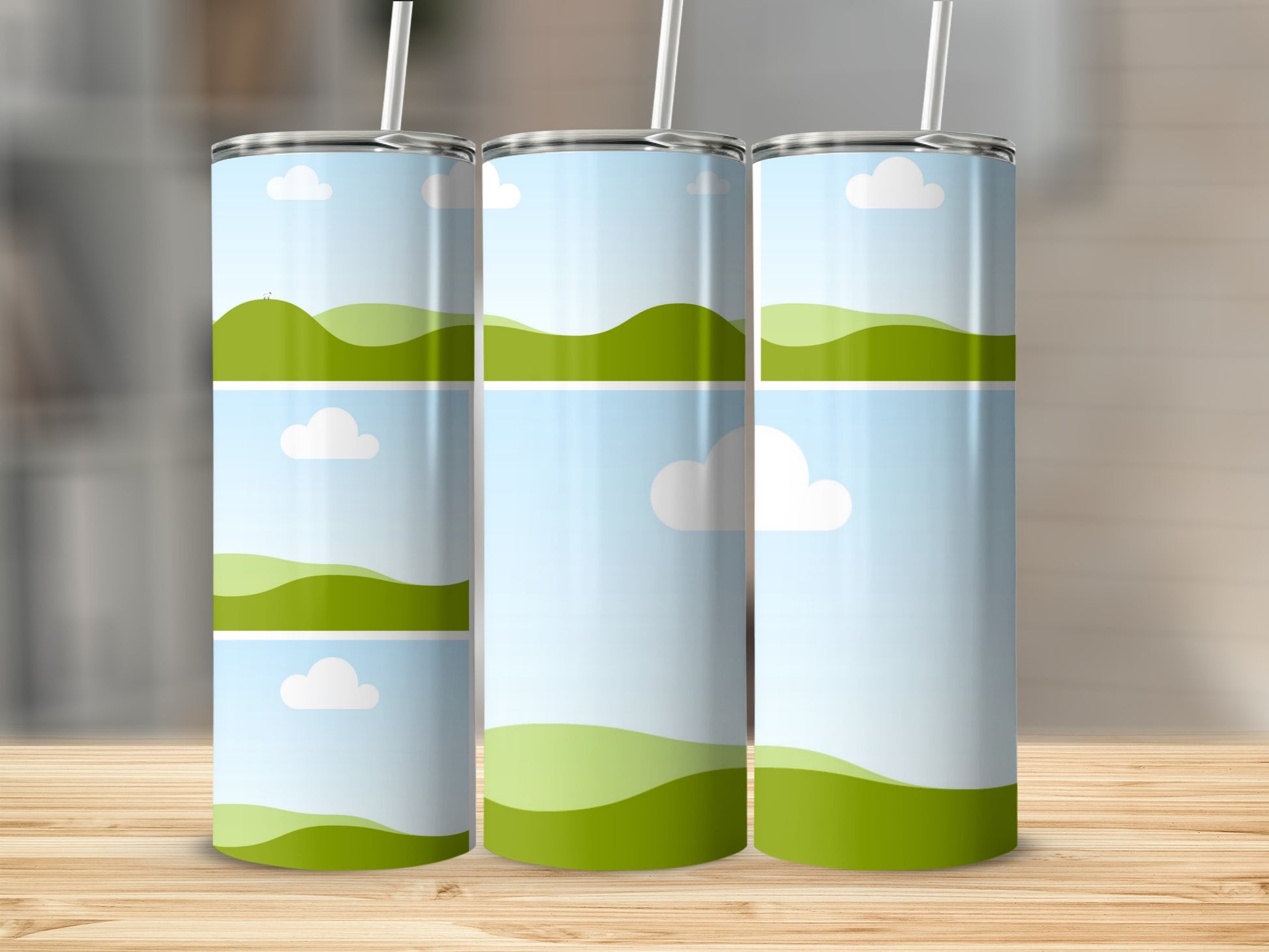 Three tumblers with a cartoon landscape design of green hills and clouds.