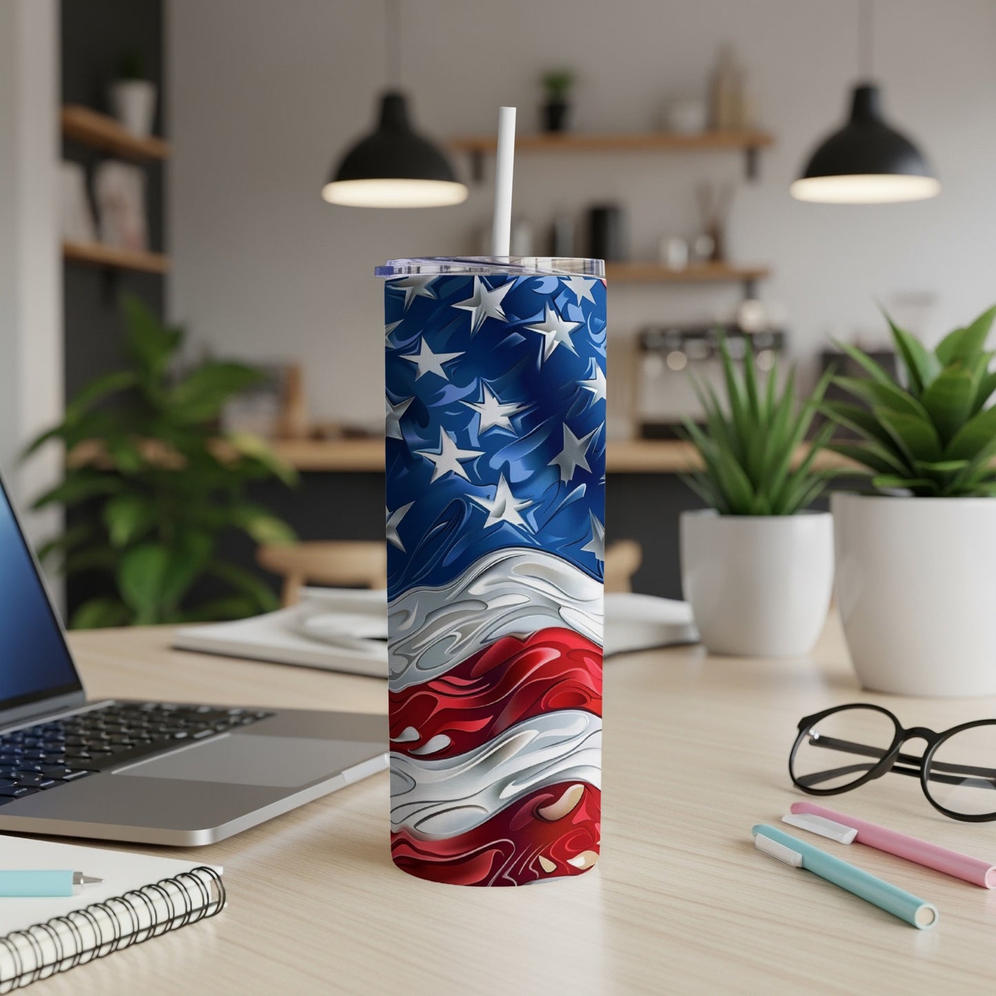 American flag tumbler with straw on a wooden desk with laptop and plants.
