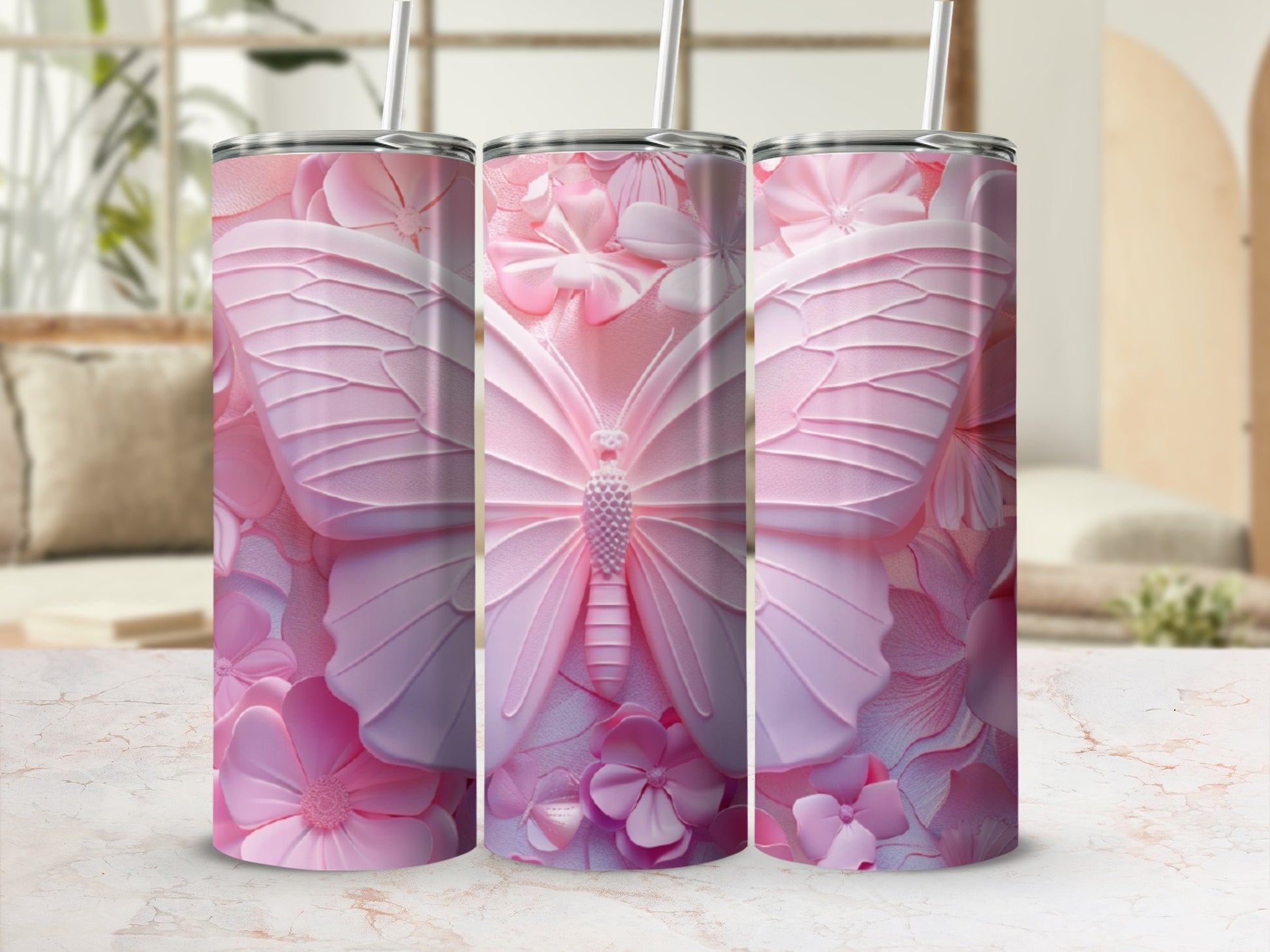 Pink butterfly and floral design on three tumblers with straws.