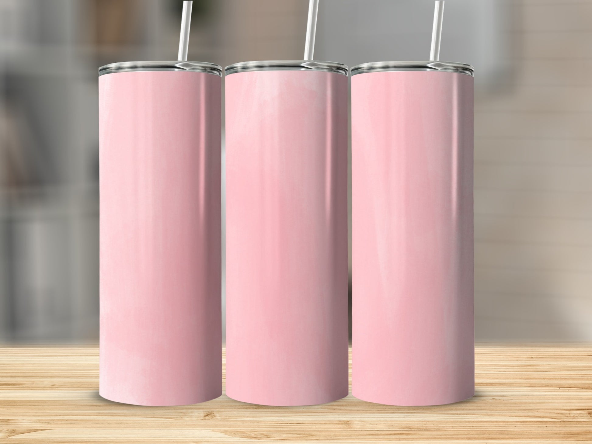 Three tall pink tumblers with white straws on a wooden surface.