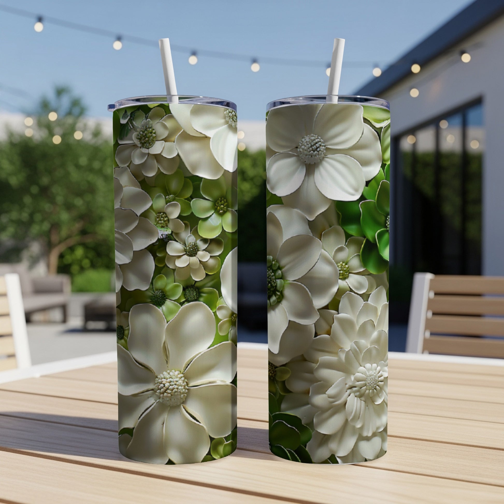Two white floral print tumblers with straws on a wooden table.