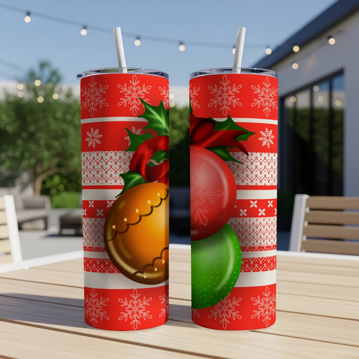 Two Christmas-themed tumblers with ornaments and snowflakes on a wooden table.