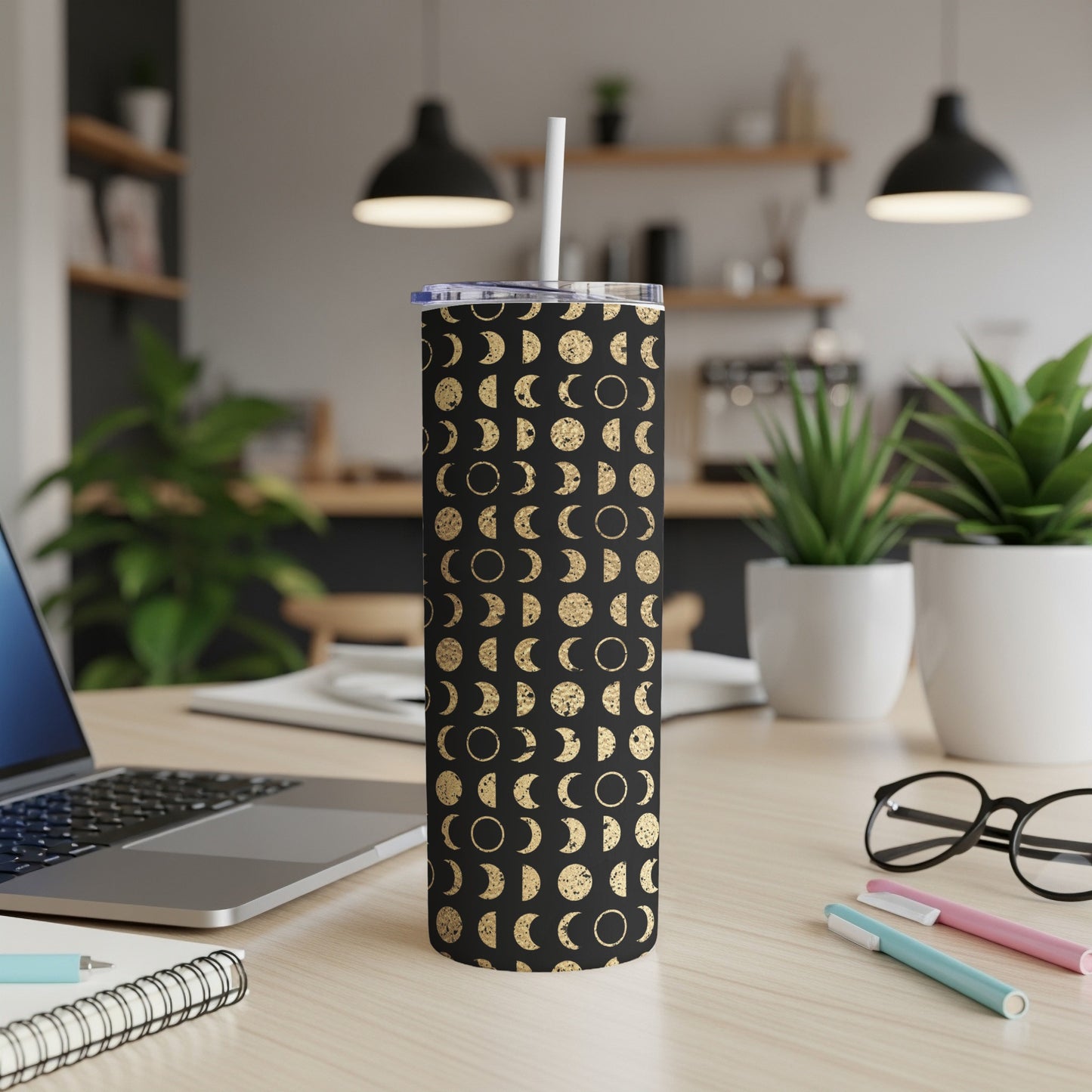 Black tumbler with gold moon phase pattern and white straw.