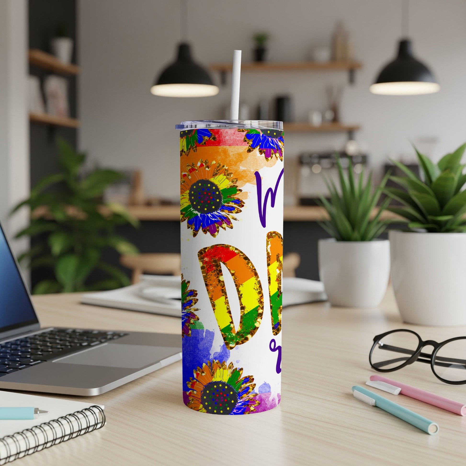 Rainbow sunflower tumbler with "Pride" text on a desk.