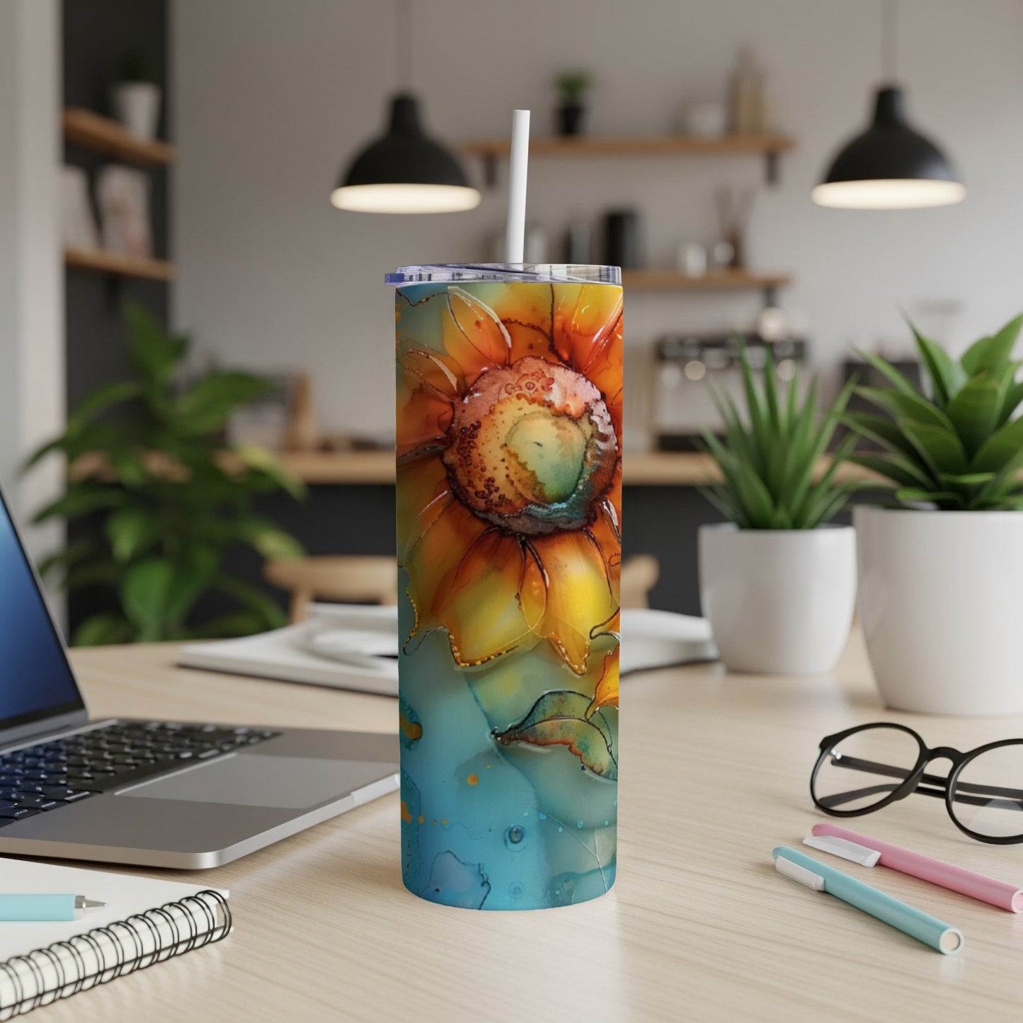 Sunflower tumbler with straw on a desk, laptop, and office supplies.