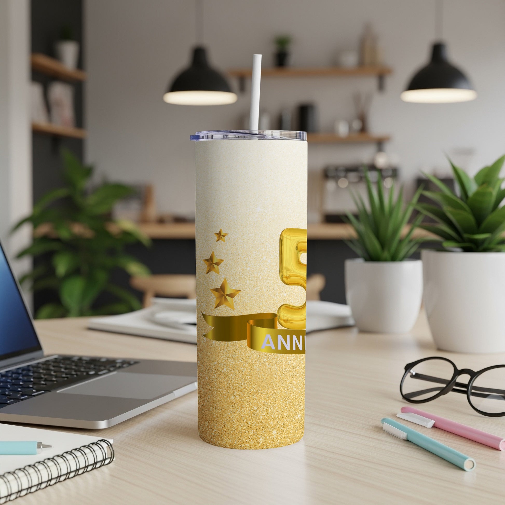 Gold glitter tumbler with "5th ANNIVERSARY" text on a desk.