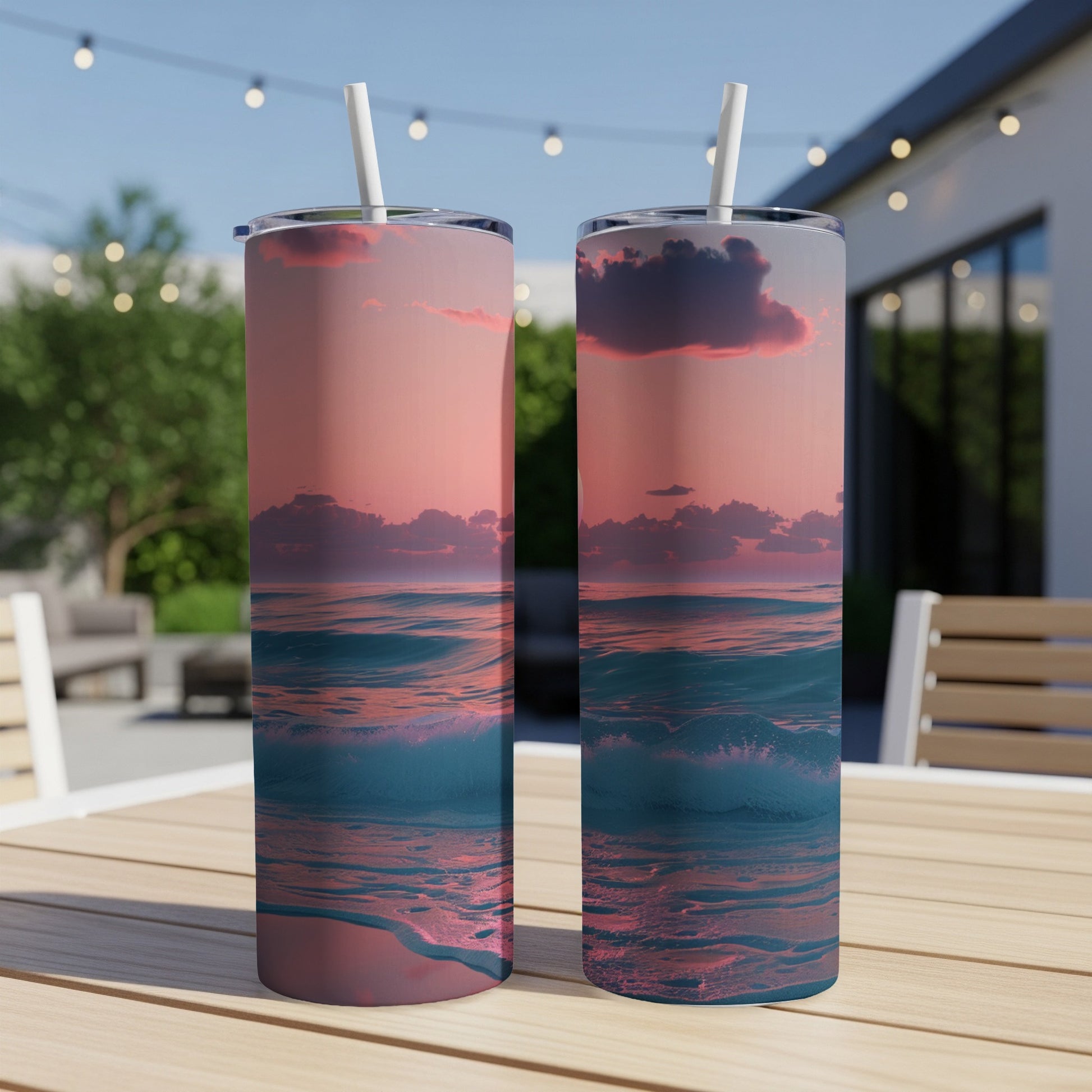 Two tall tumblers with a sunset ocean wave design sit on a table.