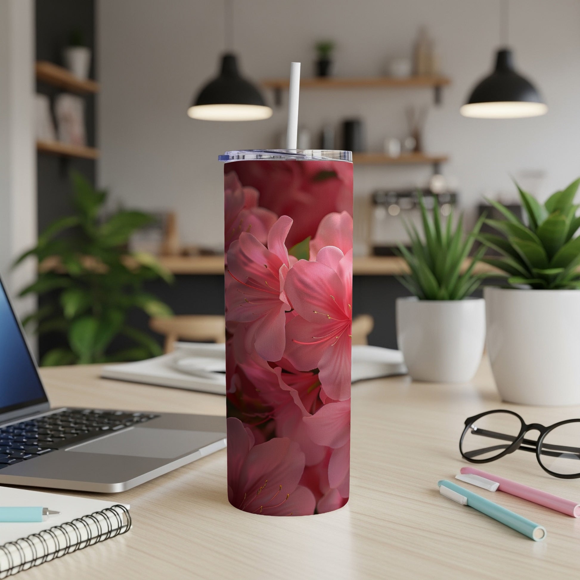 Pink azalea flowers cover a white skinny tumbler with a straw.