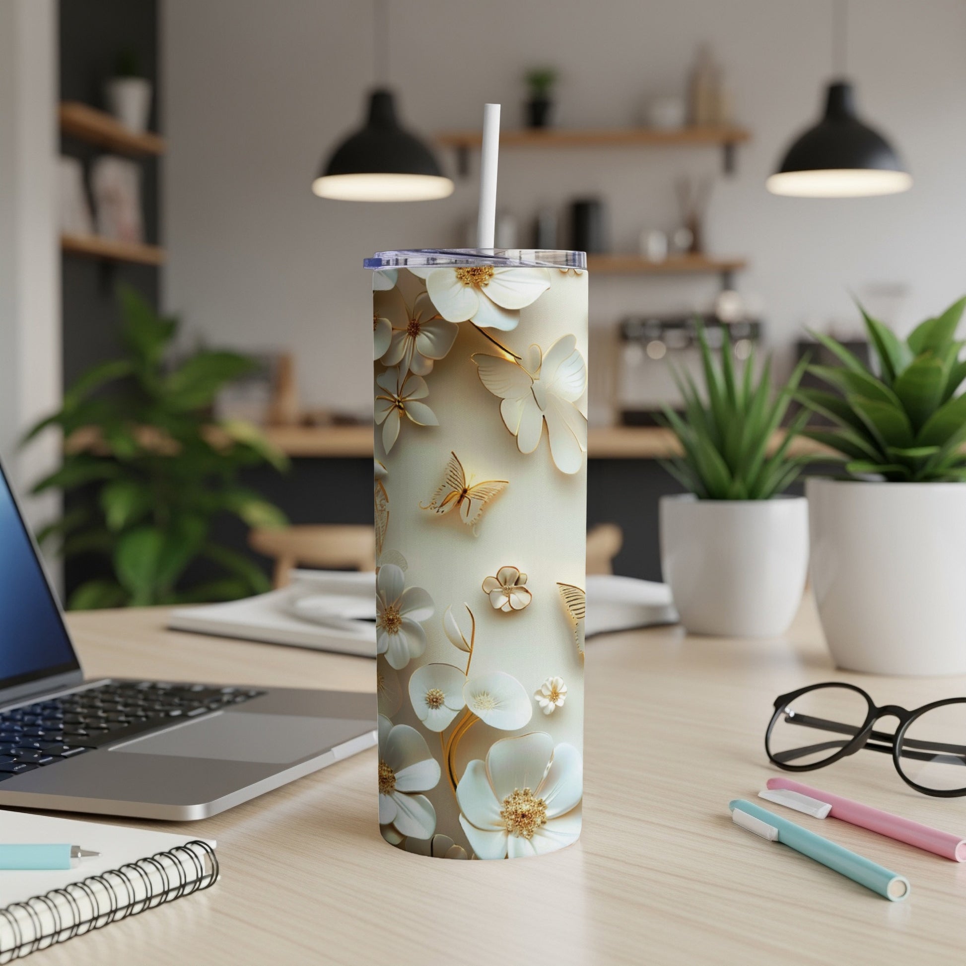 Floral and butterfly patterned tumbler with a straw on a wooden desk.