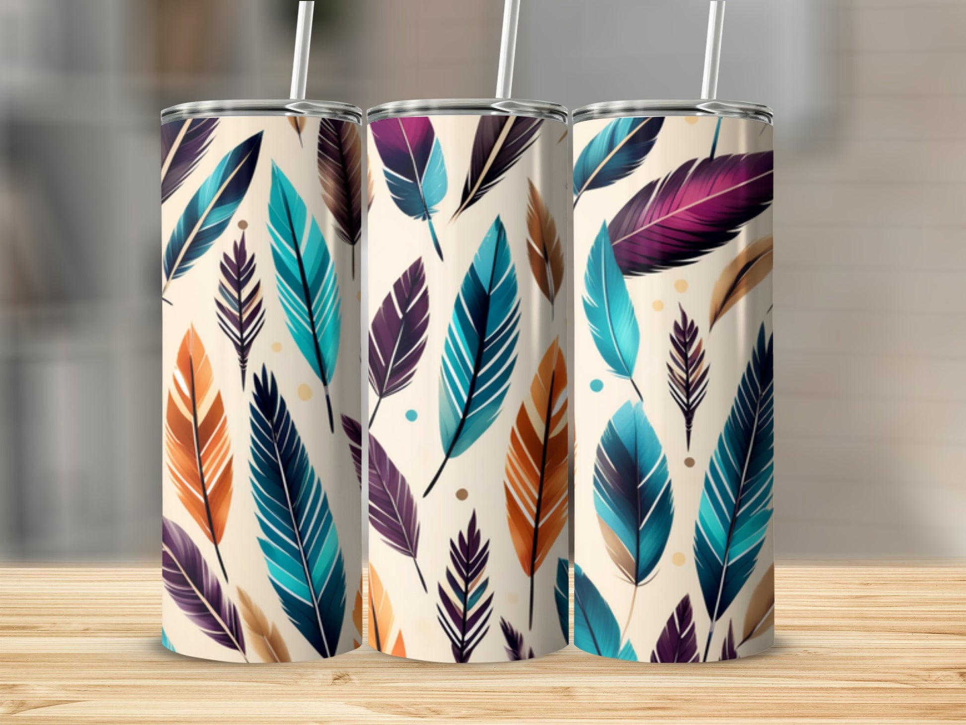 Three tumblers with colorful feather designs on a wooden surface.