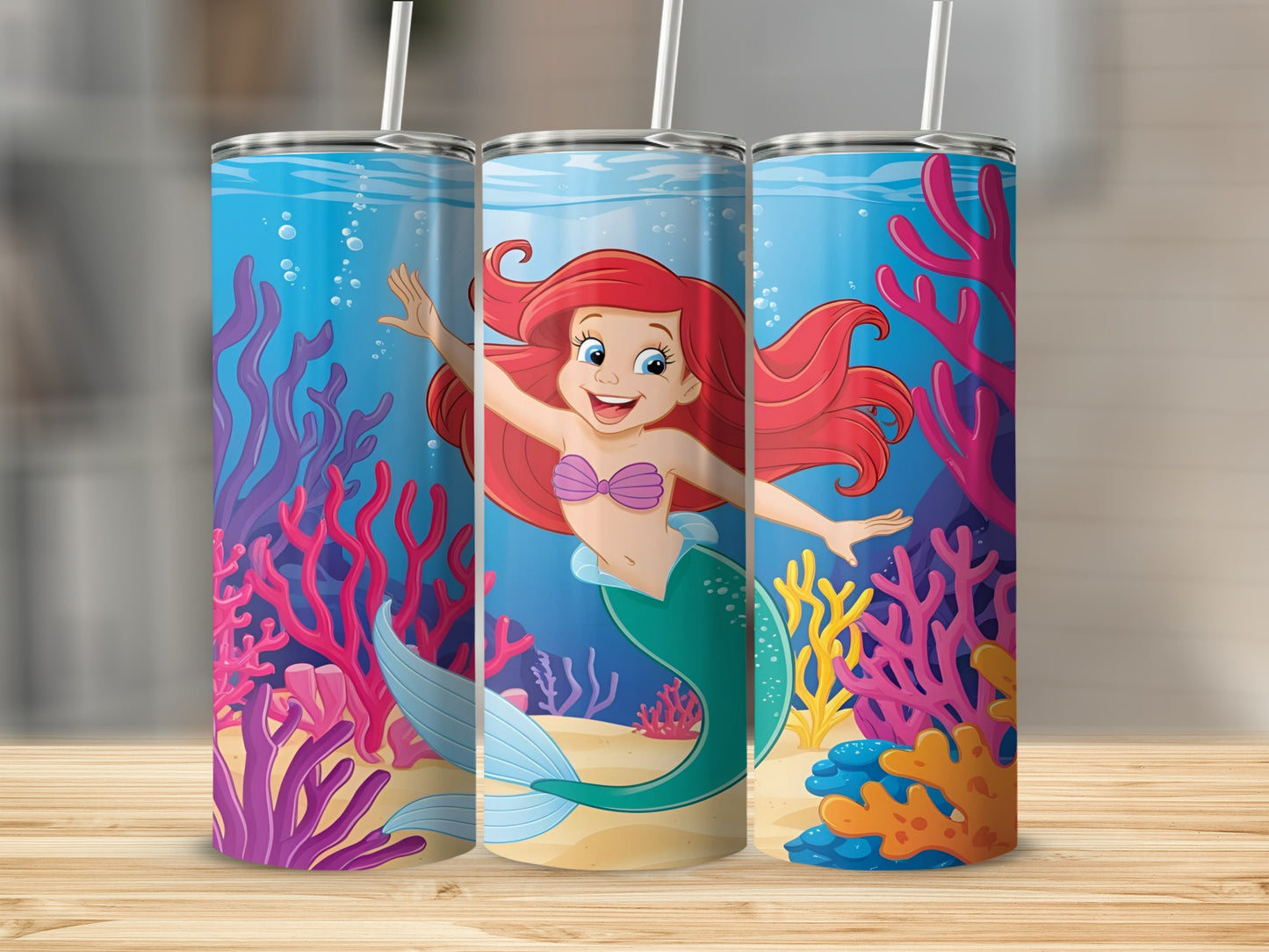 Ariel the mermaid smiles and waves on a blue tumbler with coral and sea life.