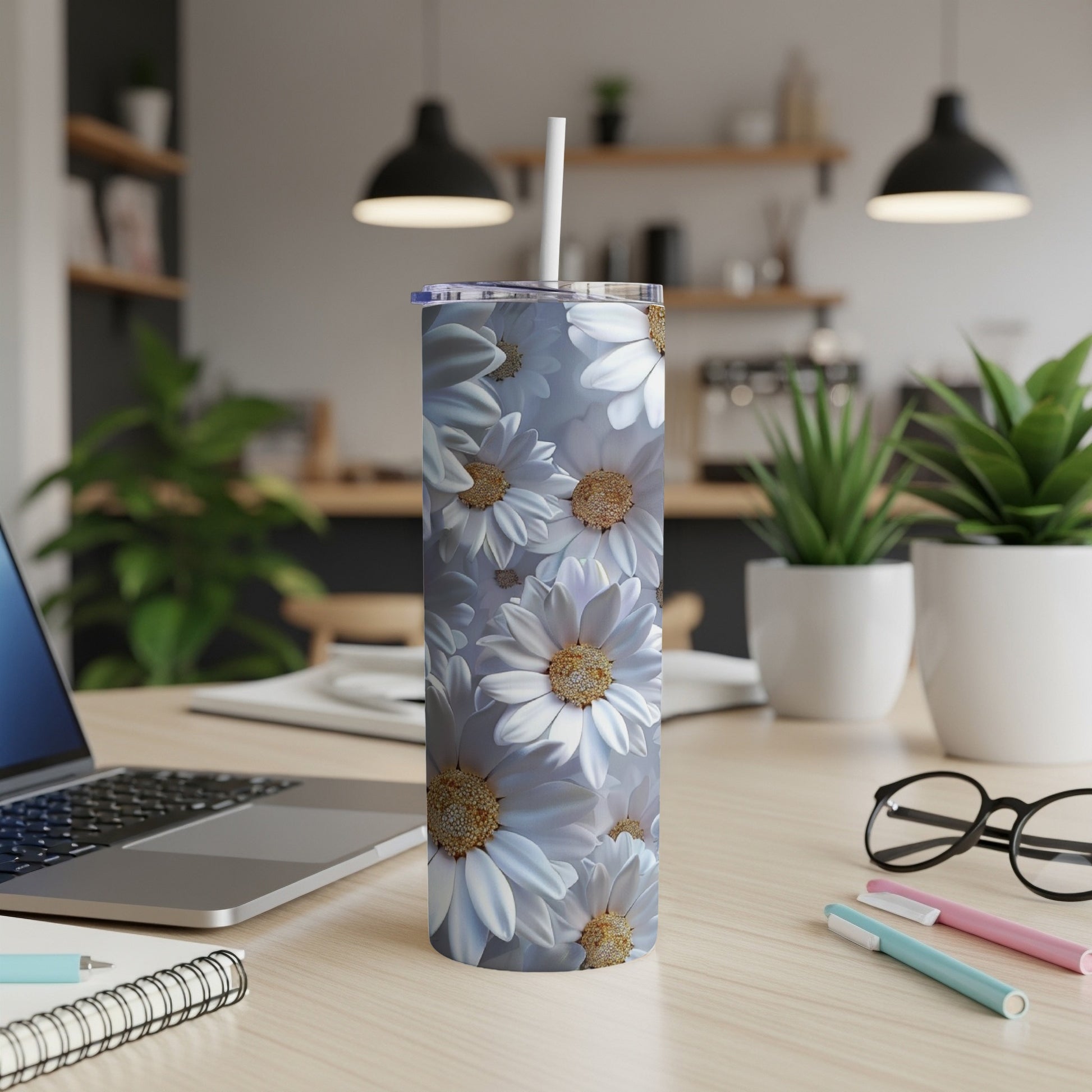 Tall tumbler with white daisy floral pattern on a desk.