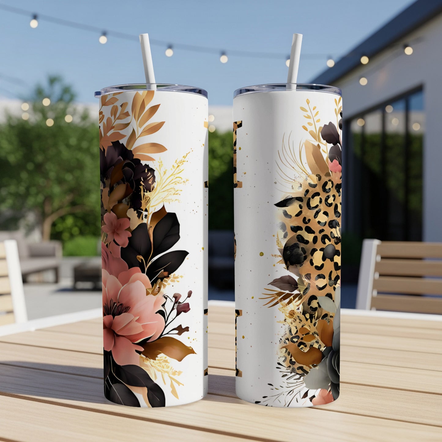 Two white tumblers with floral and leopard print designs on a wooden table outdoors.