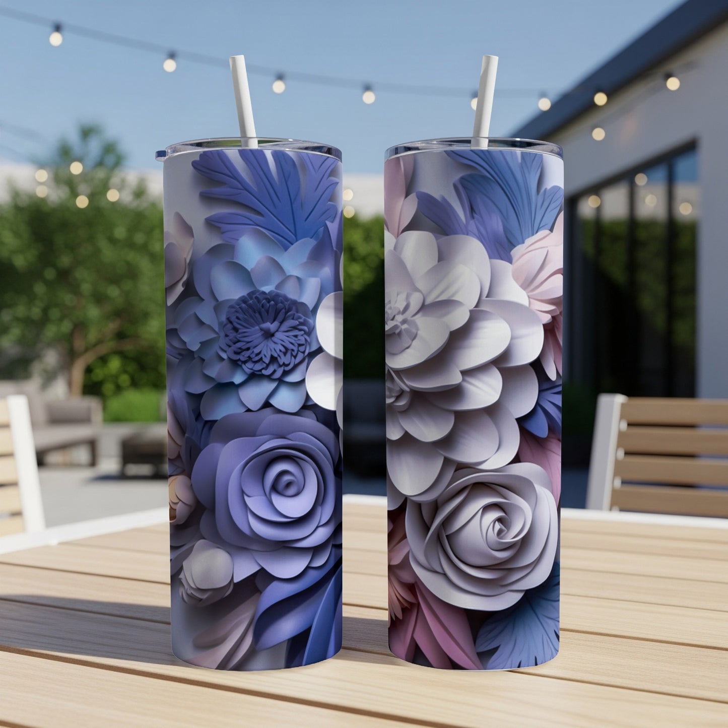 Two tall floral tumblers with straw on outdoor table.