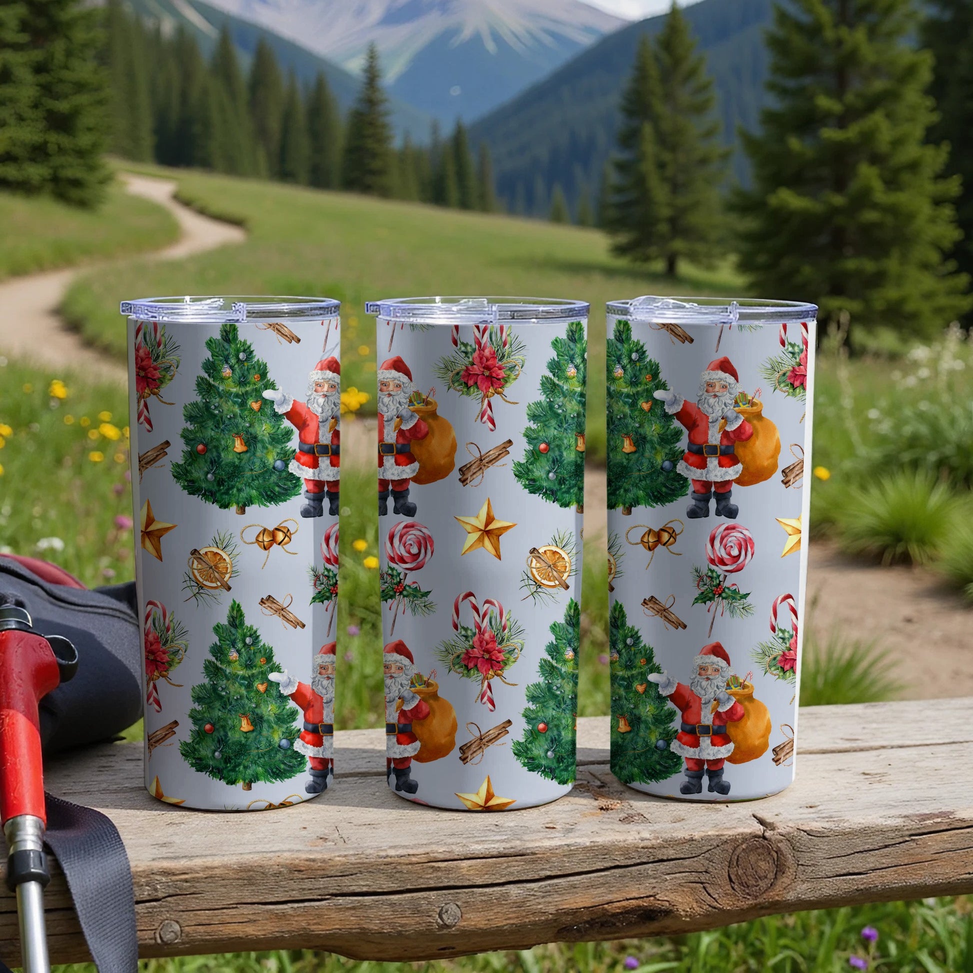 Three Santa Claus and Christmas tree patterned tumblers on a wooden surface.