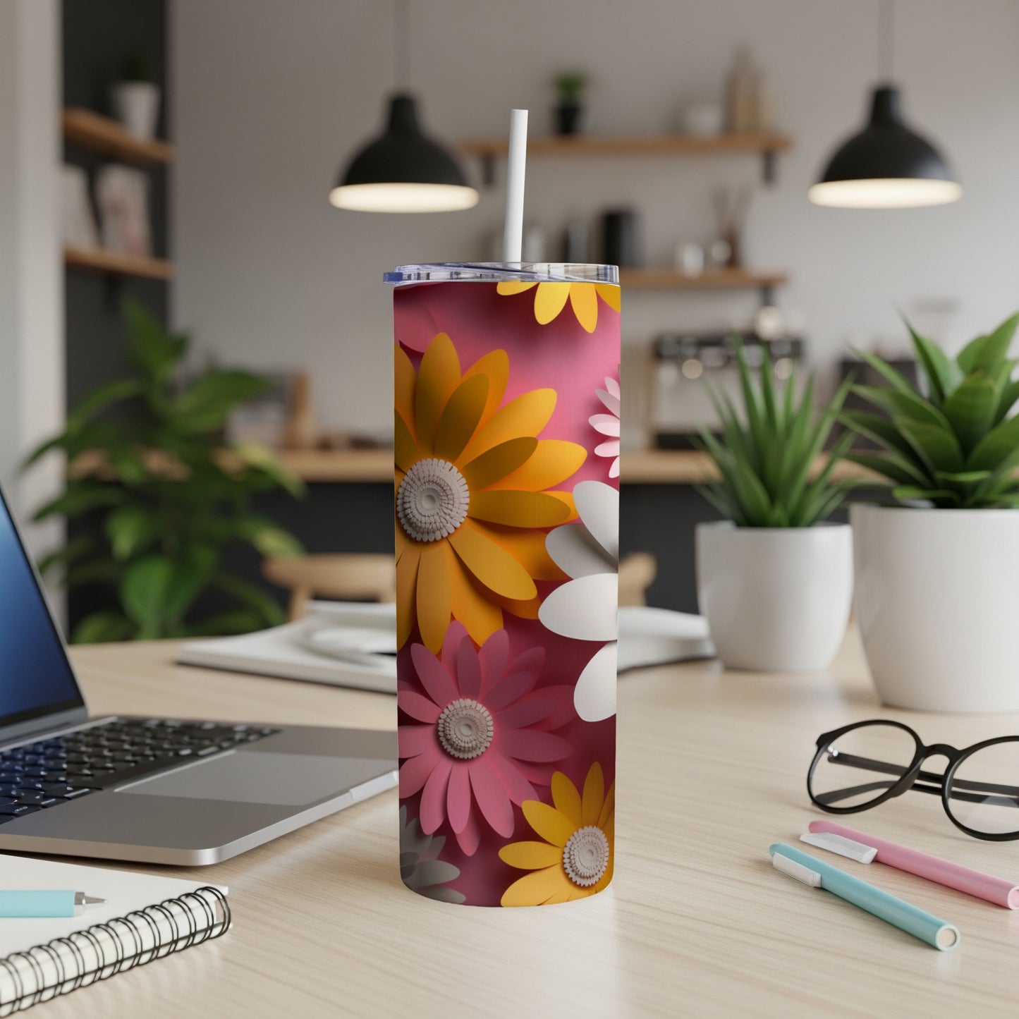 Pink tumbler with colorful floral pattern on a desk.