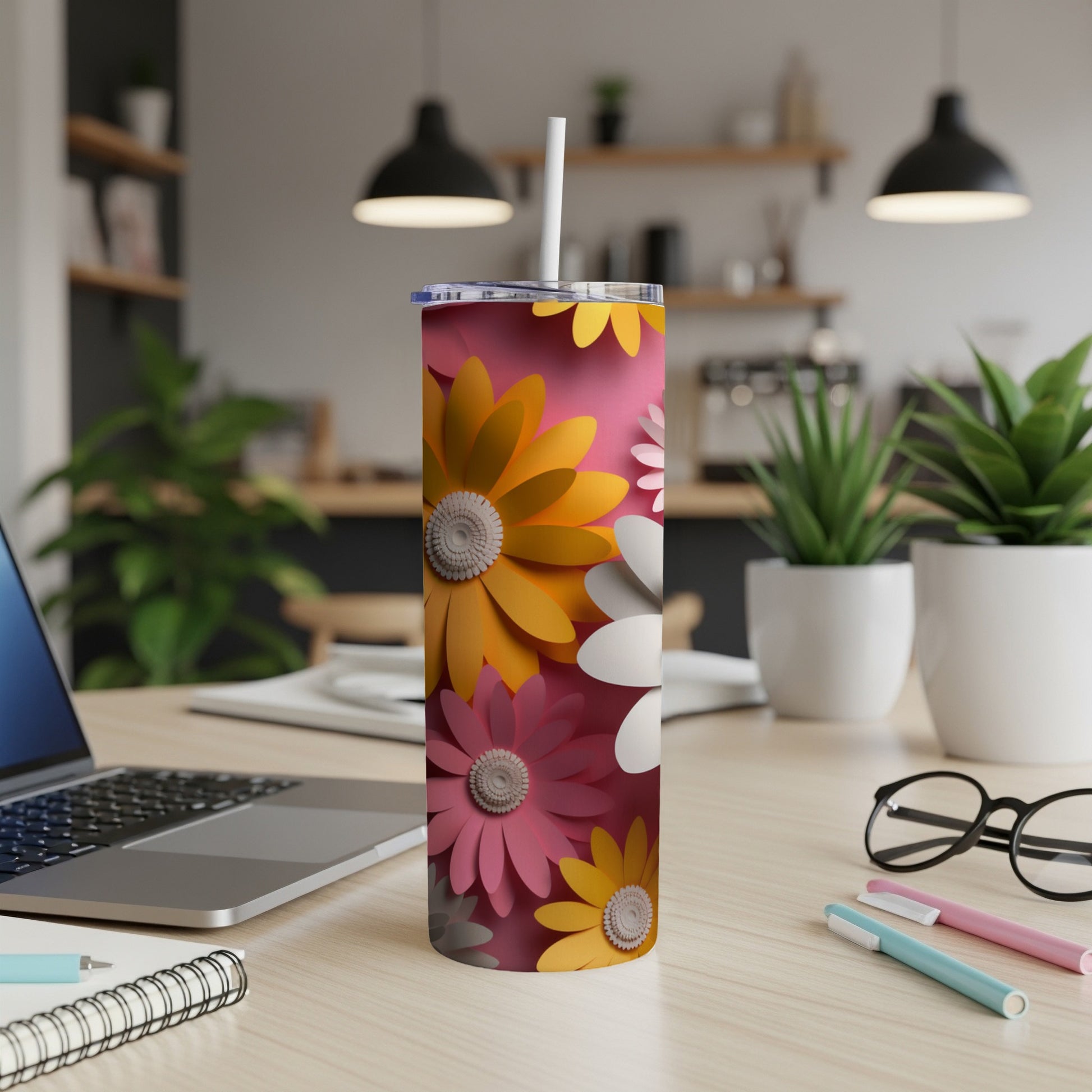 Pink tumbler with colorful floral pattern on a desk.