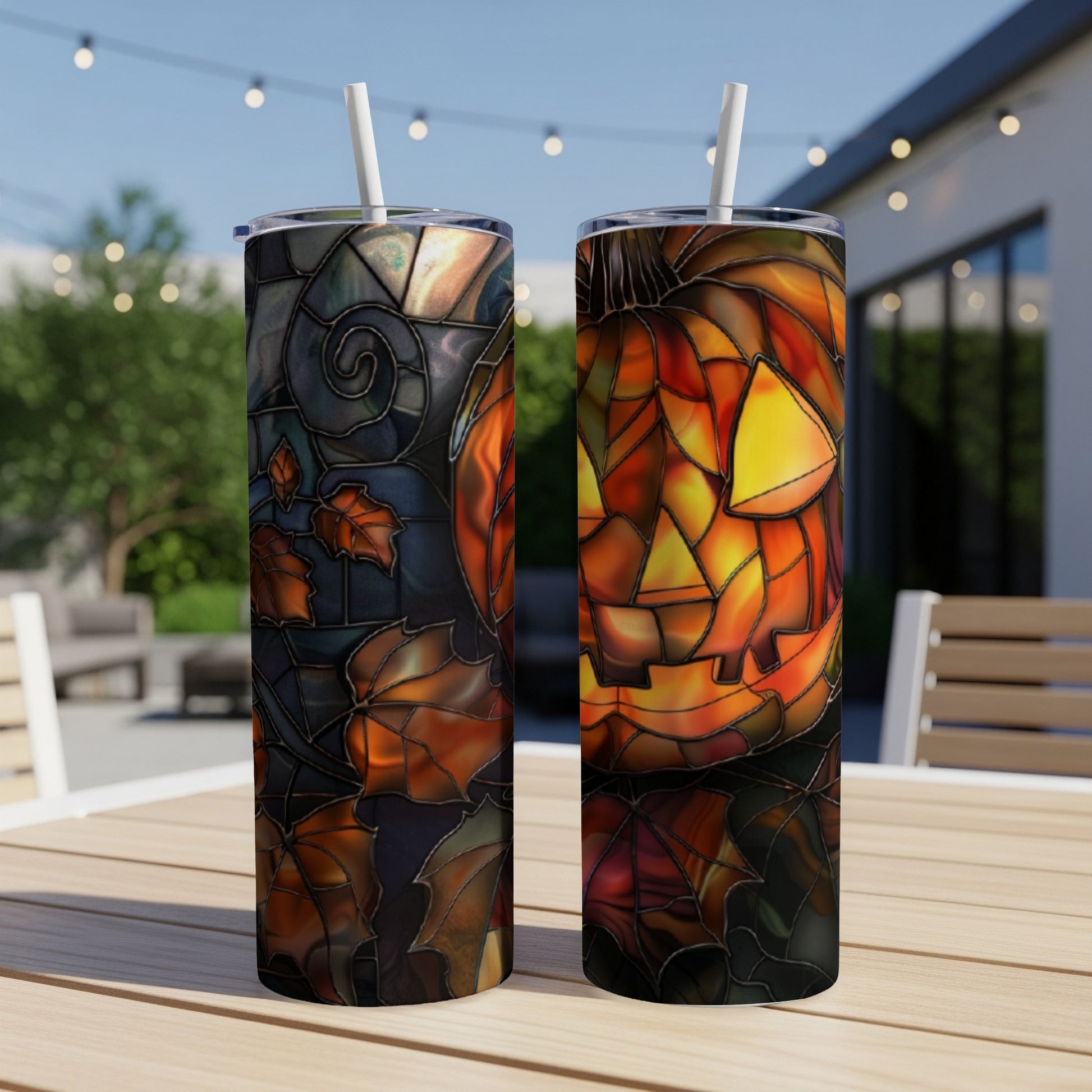 Two tumblers with Halloween pumpkin stained glass designs on outdoor table.