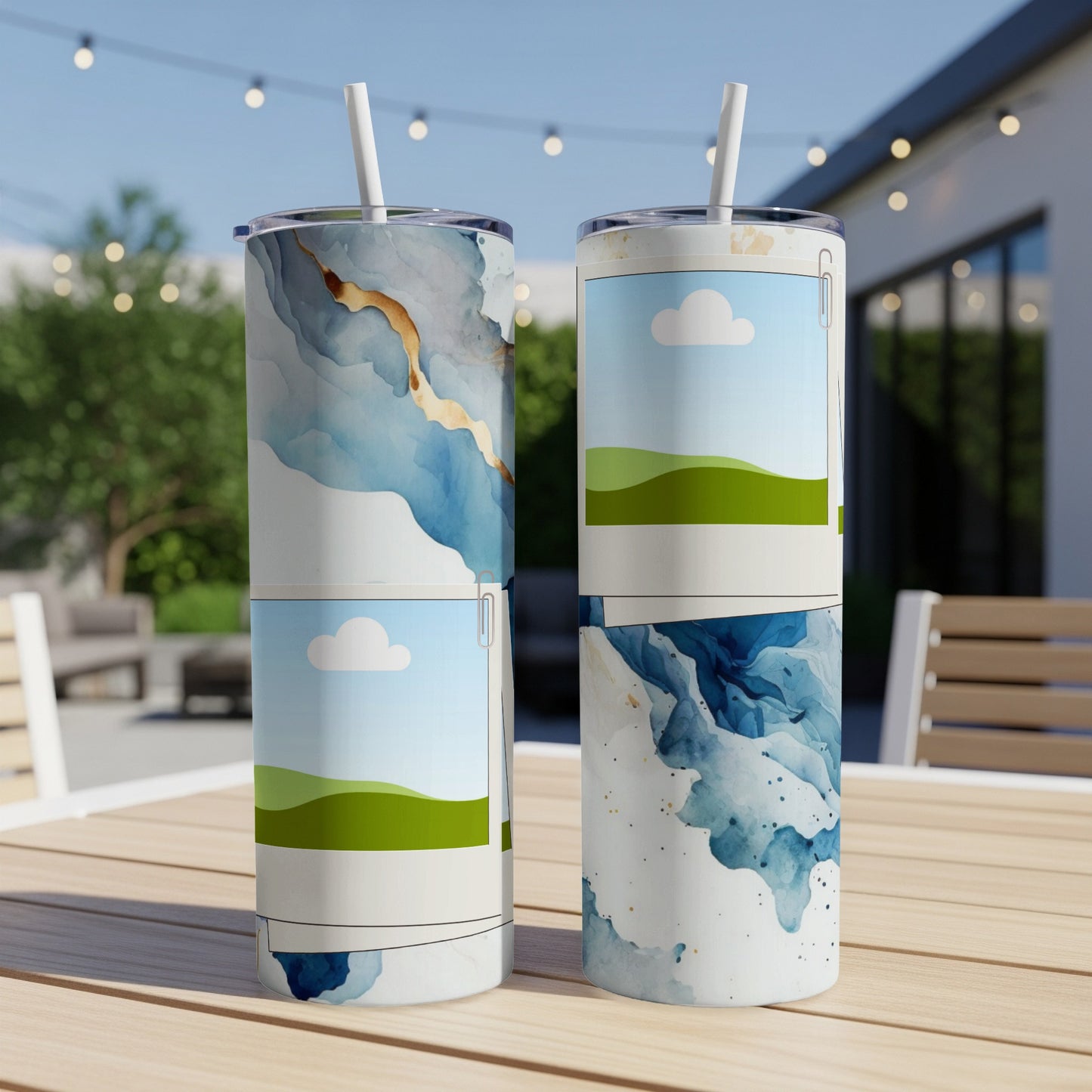 Two tumblers with abstract watercolor designs and picture frames on a wooden table.
