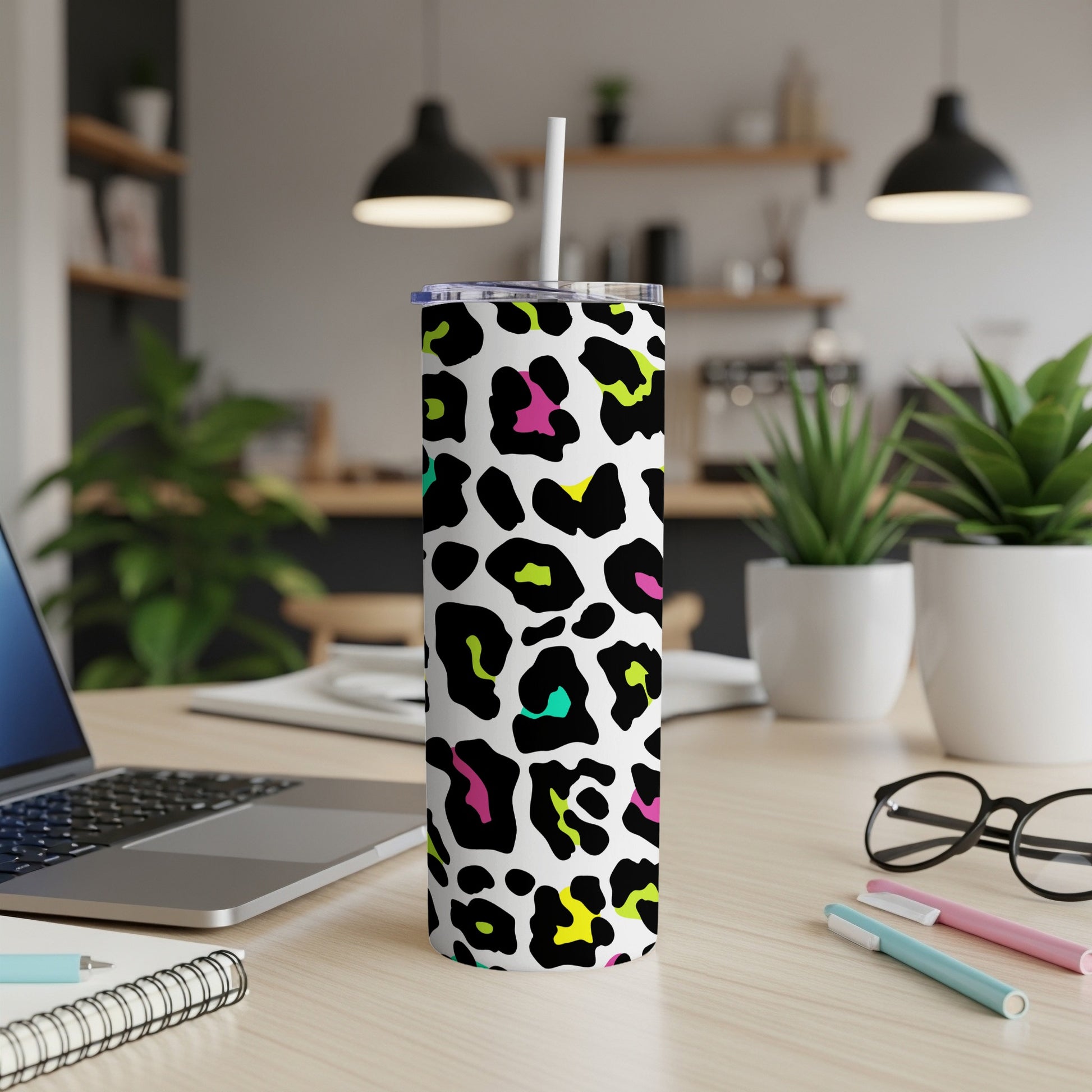 Tall tumbler with white background and colorful leopard print, featuring a straw.