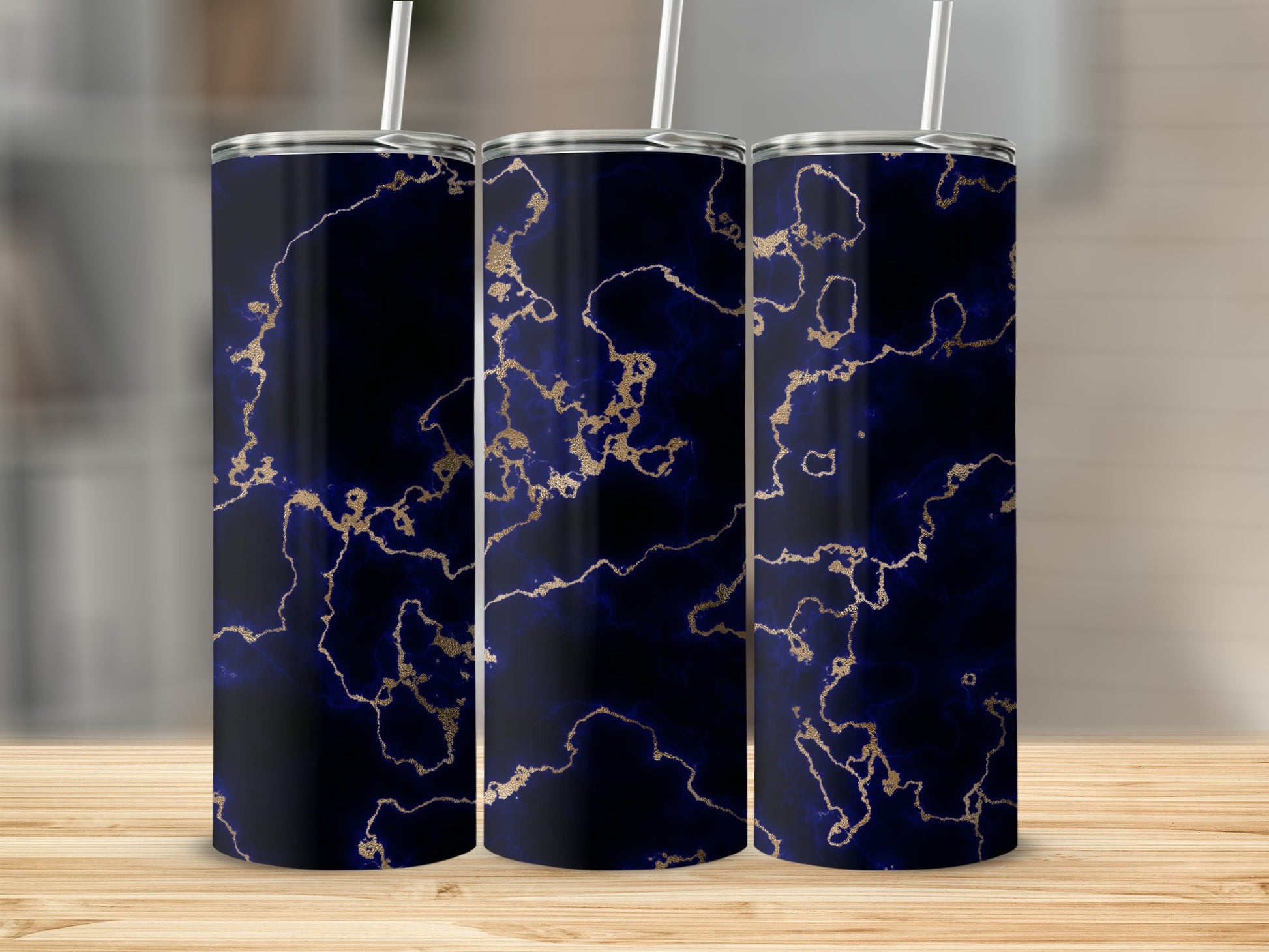 Three dark blue tumblers with gold veining sit on a wooden surface.