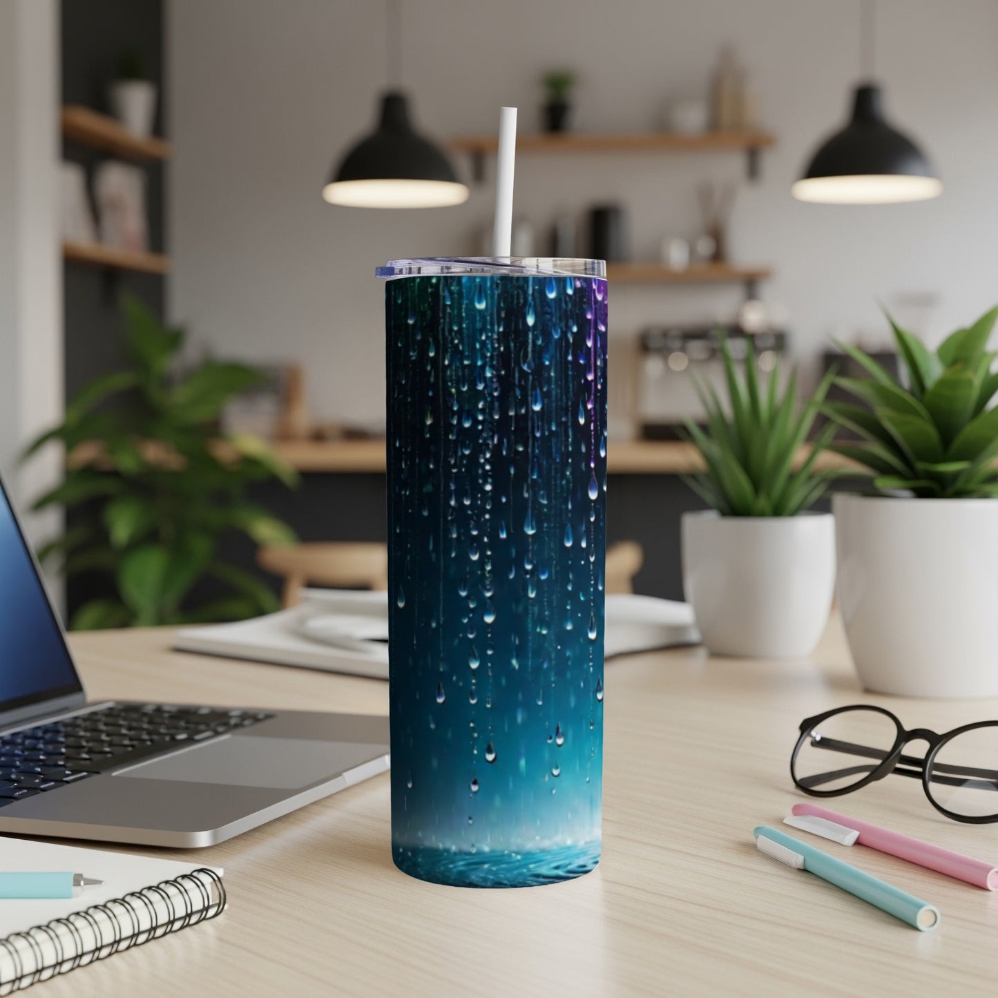 Blue tumbler with water droplet design and straw on a desk.