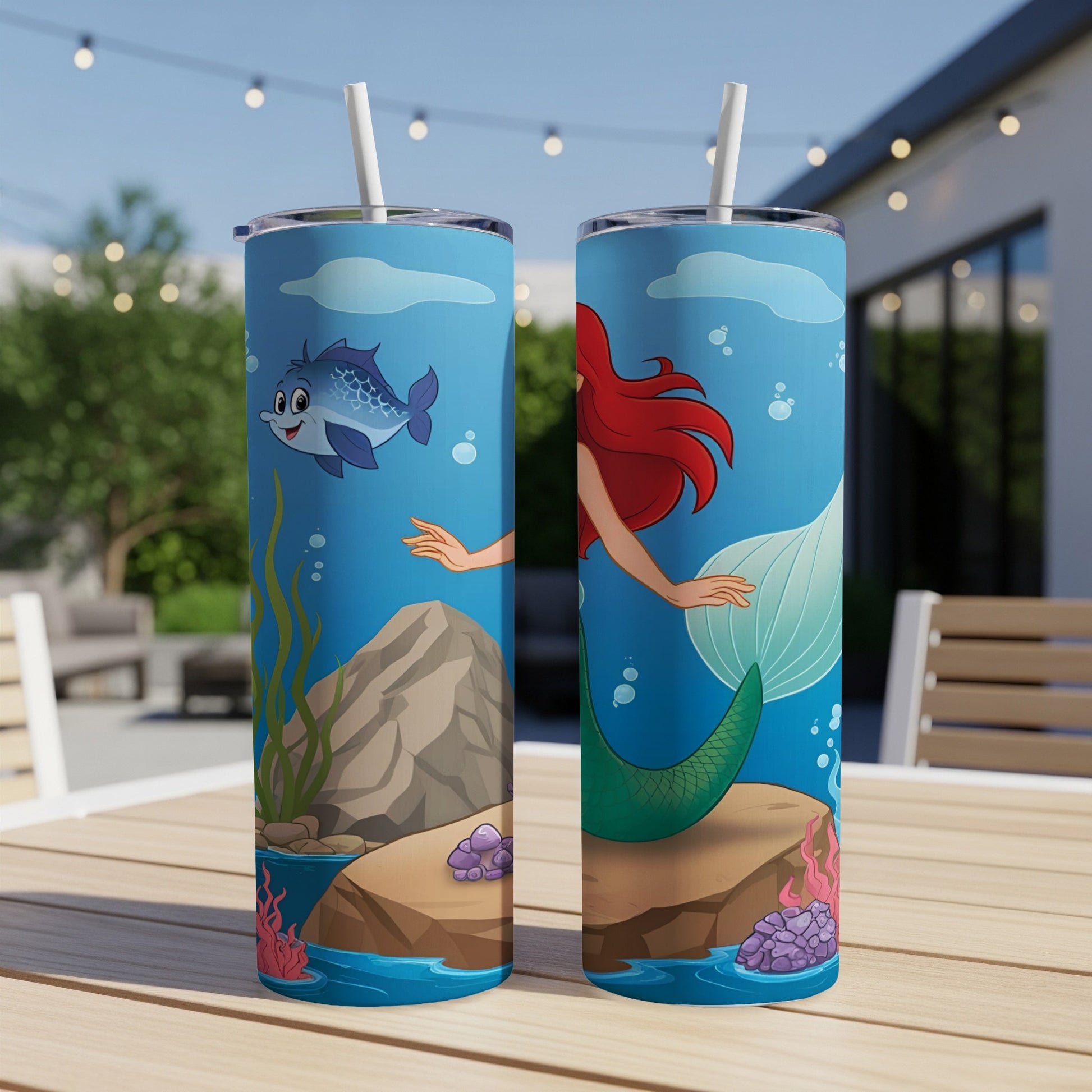 Two mermaid tumblers with cartoon fish, seaweed, and rocks against a blue background.